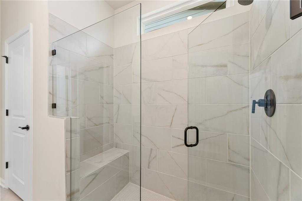 Frameless glass walk-in shower with white subway tile, built-in bench, and black fixtures in Davidson Homes The Daphne C master bath, Loganville, GA