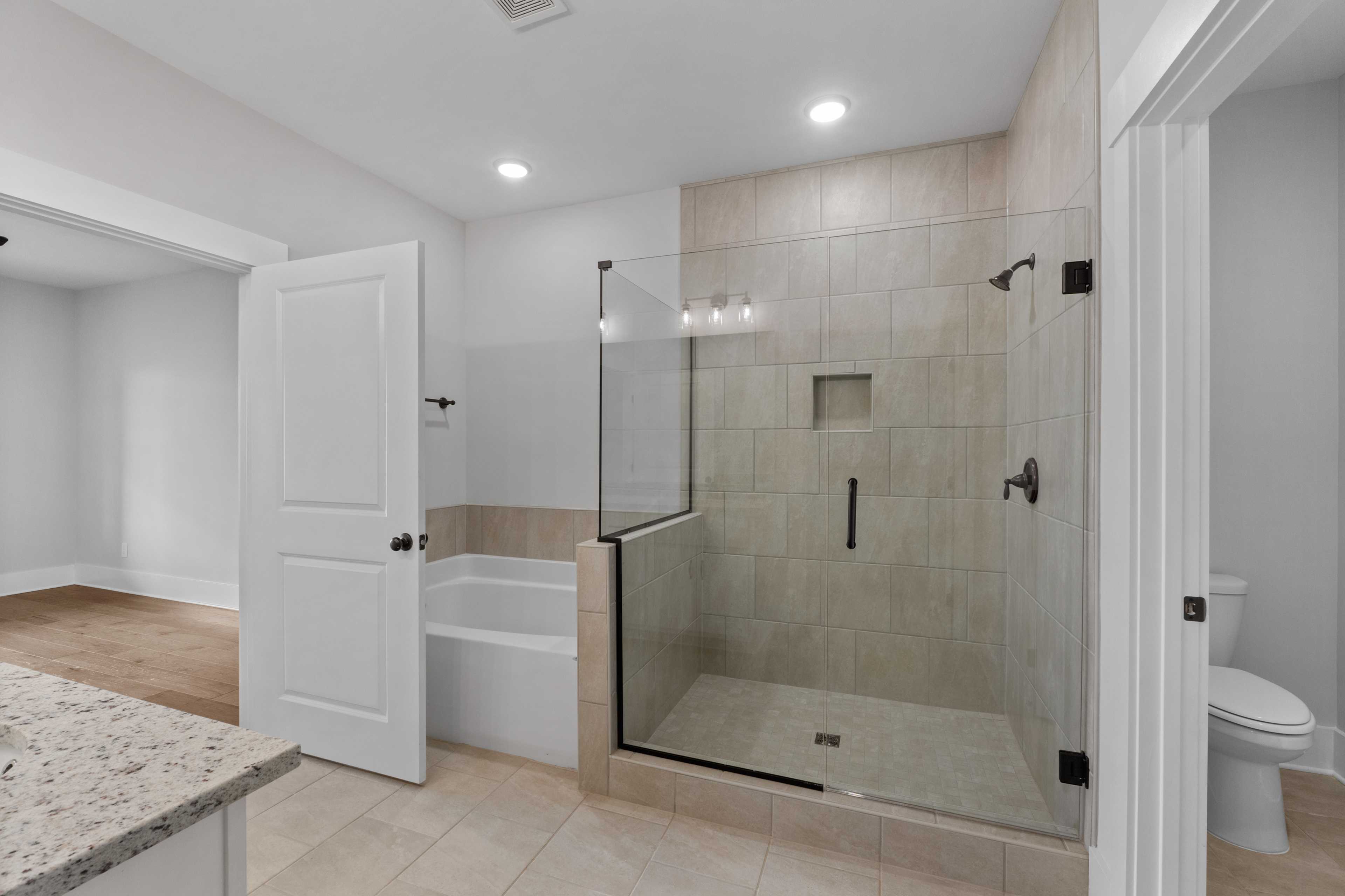 Spacious modern bathroom at The Villas at Barnett's Crossing in Madison AL with glass shower, soaking tub, and granite vanity
