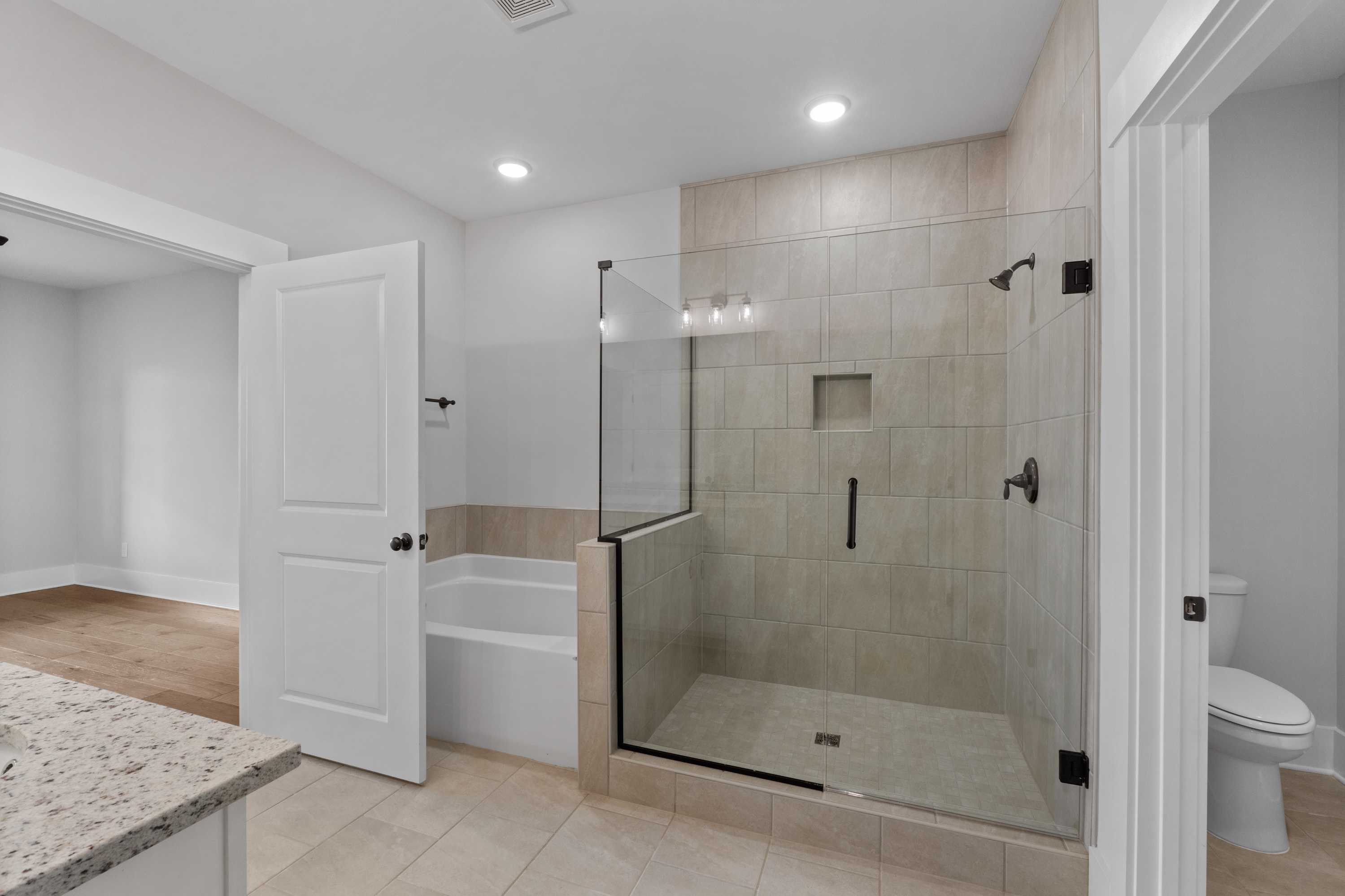 Spacious modern bathroom at The Villas at Barnett's Crossing in Madison AL with glass shower, soaking tub, and granite vanity