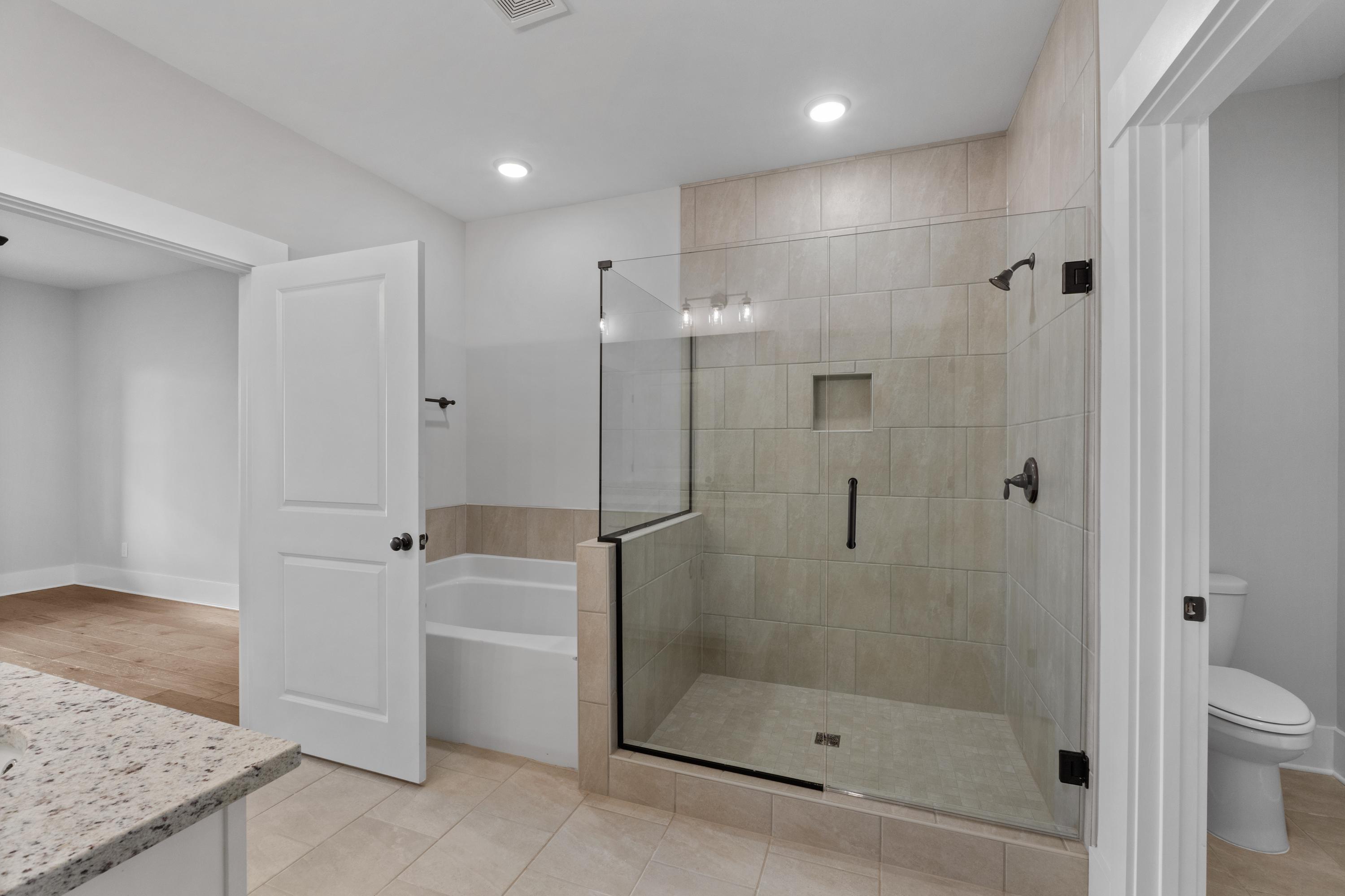 Spacious modern bathroom at The Villas at Barnett's Crossing in Madison AL with glass shower, soaking tub, and granite vanity