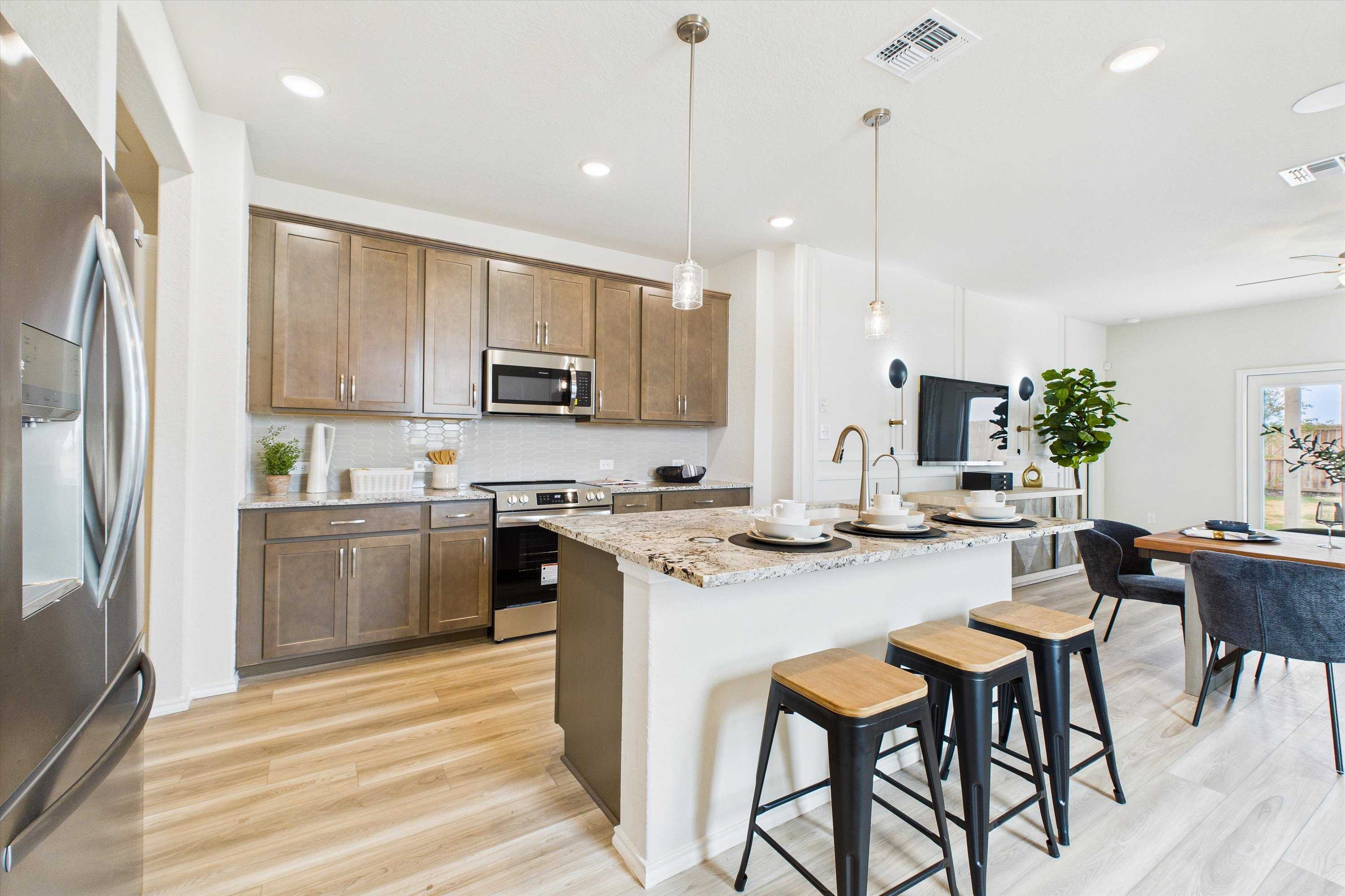 Modern open-concept kitchen at Agave in San Antonio TX with granite island, stainless appliances, and bar seating