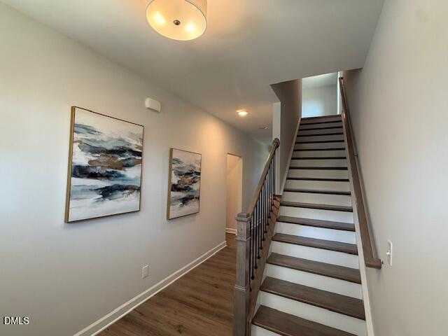 Elegant oak staircase ascending in bright foyer with abstract blue paintings, hardwood floors in Davidson Homes Preston C, Lillington NC