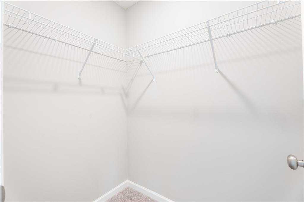 Spacious corner walk-in closet with white wire shelving in The Washington floor plan by Evermore Homes, Phenix City, Alabama