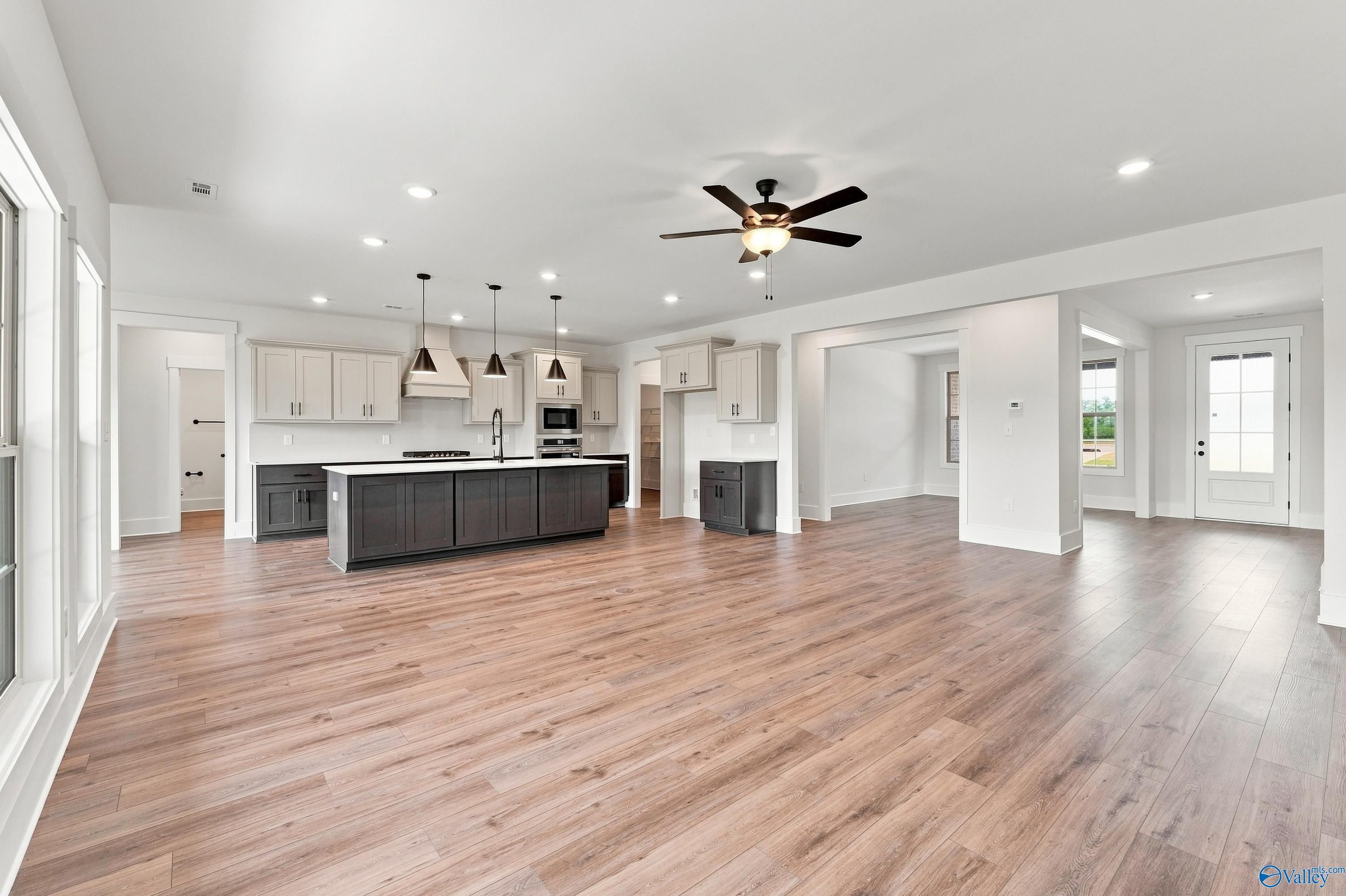 Open-concept kitchen with dark island, pendant lights, and hardwood floors in Davidson Homes The Valencia, Huntsville, Alabama