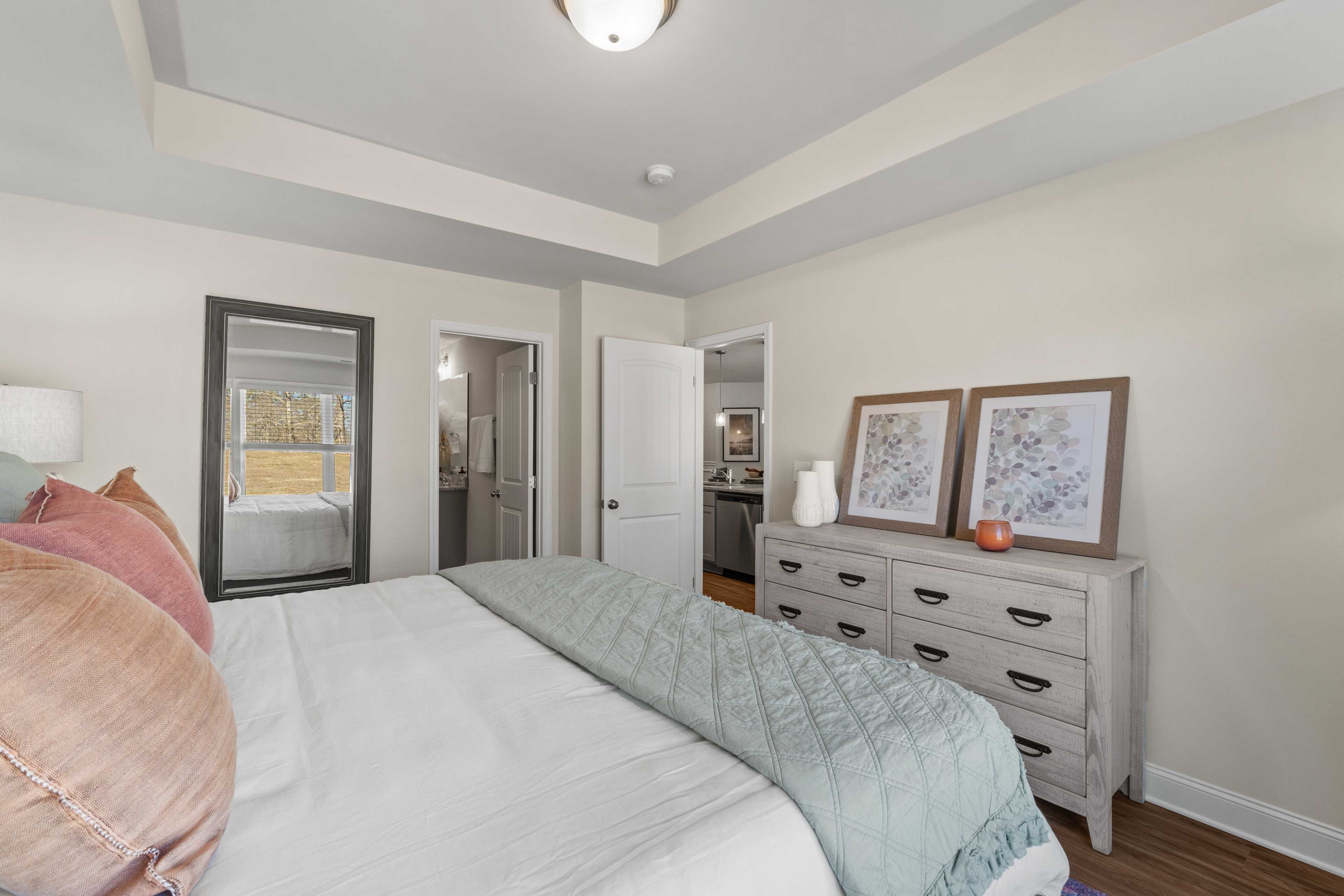 Spacious master bedroom at Ramsay Cove in Owens Cross Roads AL with king bed, teal quilt, beige dresser, framed art, and en-suite bath door