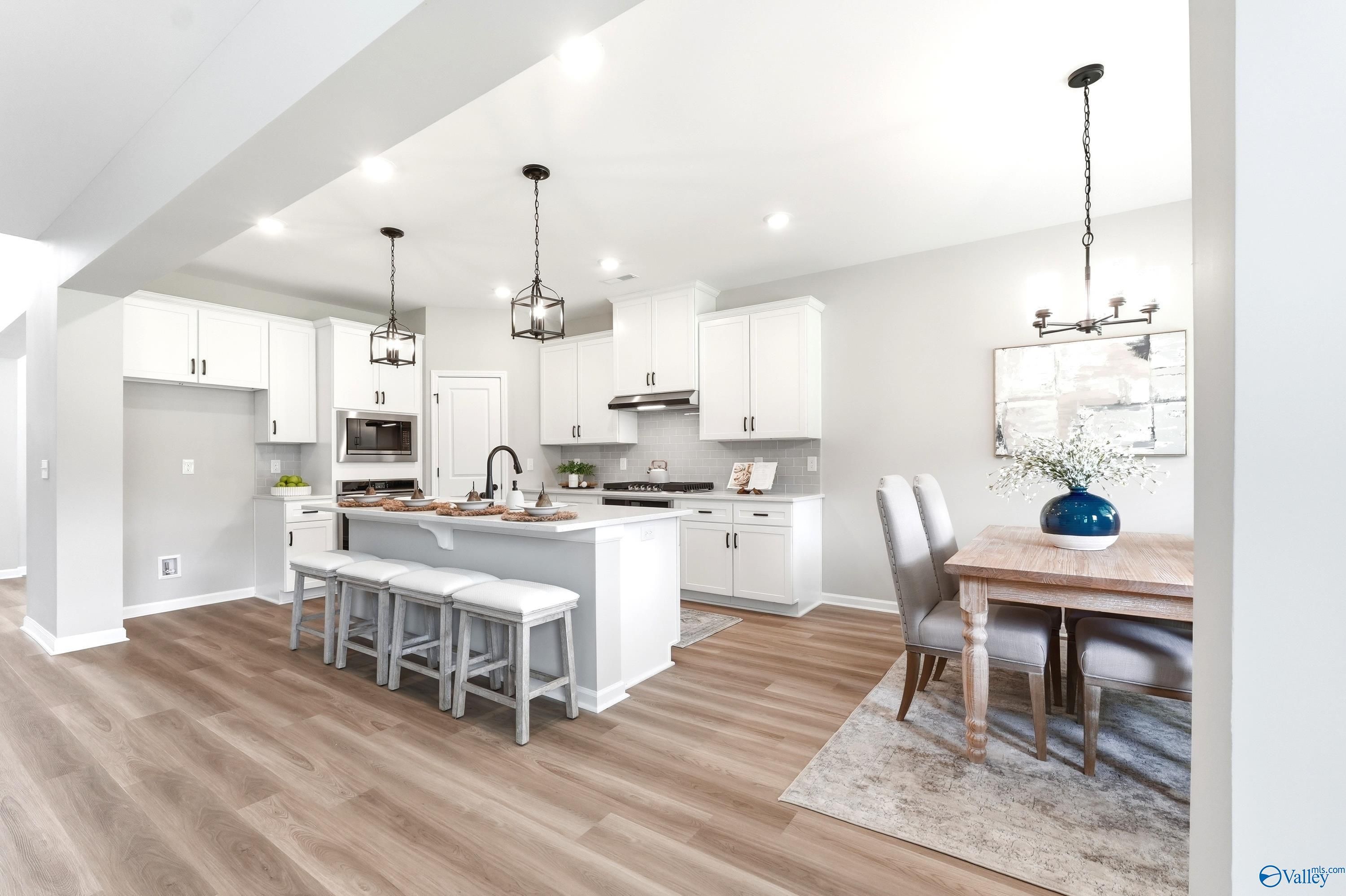 Modern white kitchen with breakfast bar and dining area in The Dorado floor plan at Riverton Preserve, Huntsville, Alabama.