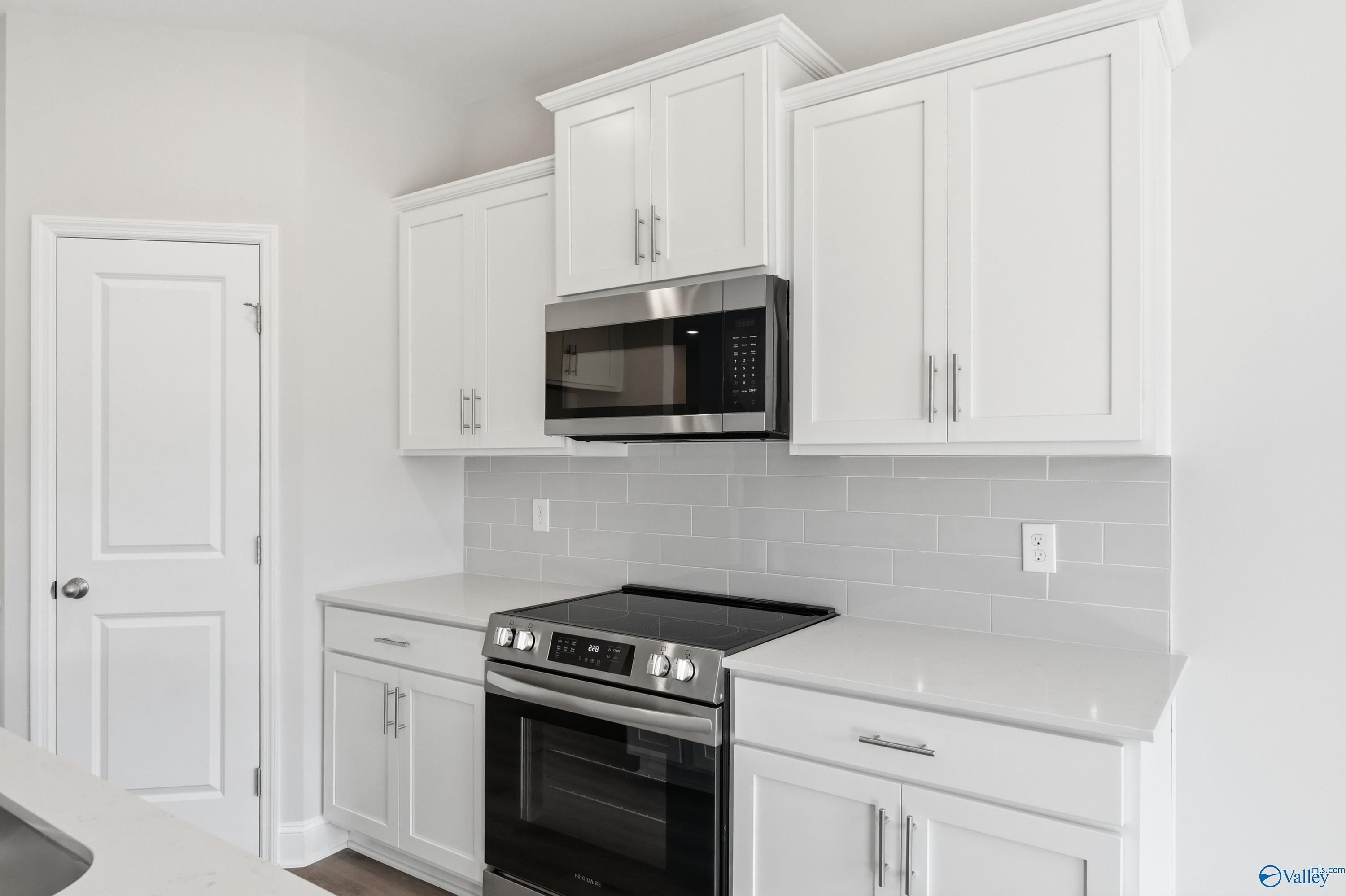 Modern kitchen featuring white shaker cabinets, stainless steel range, and gray subway tile backsplash in Davidson Homes The Asheville C, Huntsville, AL