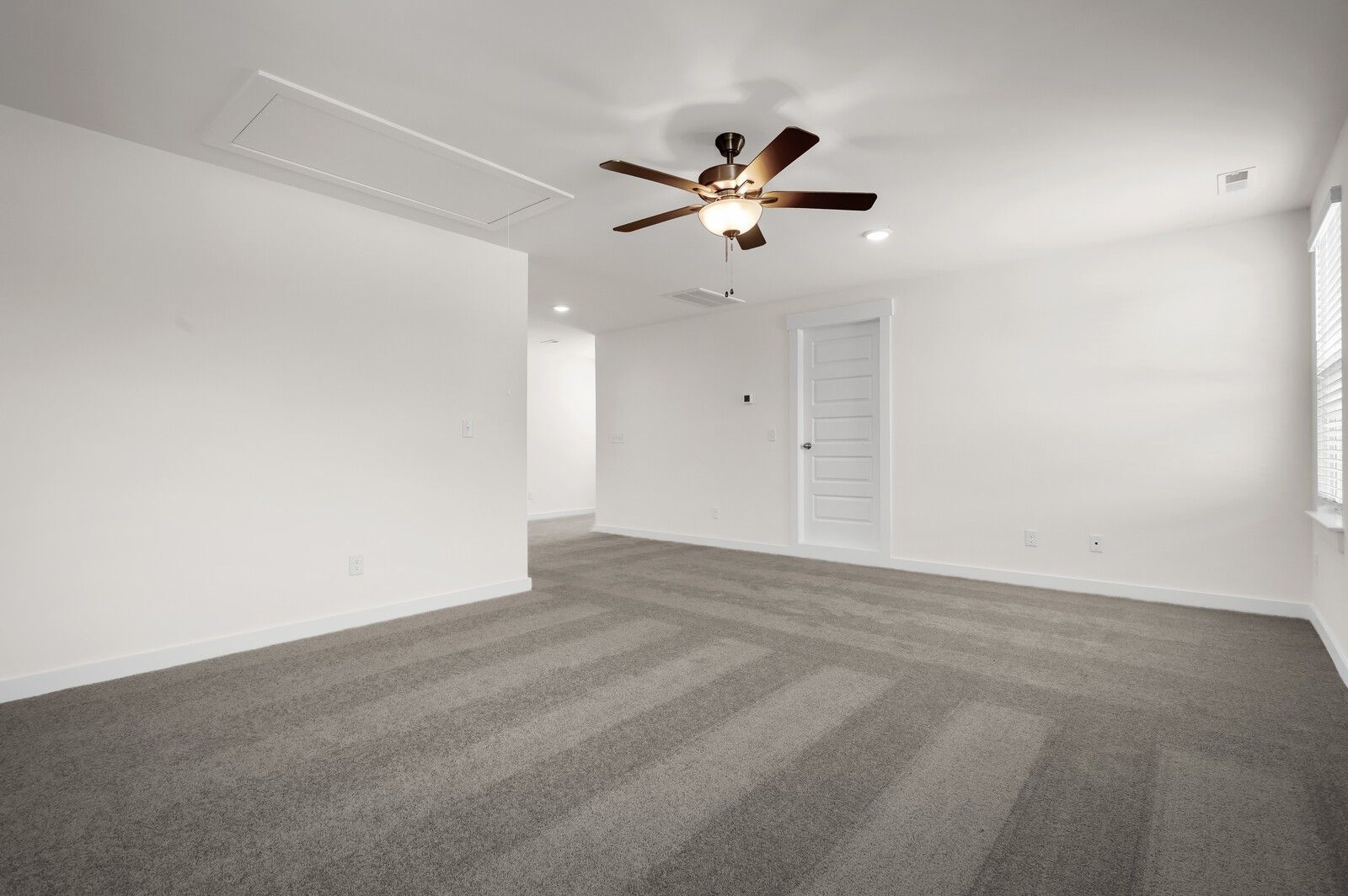 Spacious bedroom with grey carpet and ceiling fan in The Ash A floor plan at Woods Crossing, Gallatin, Tennessee.