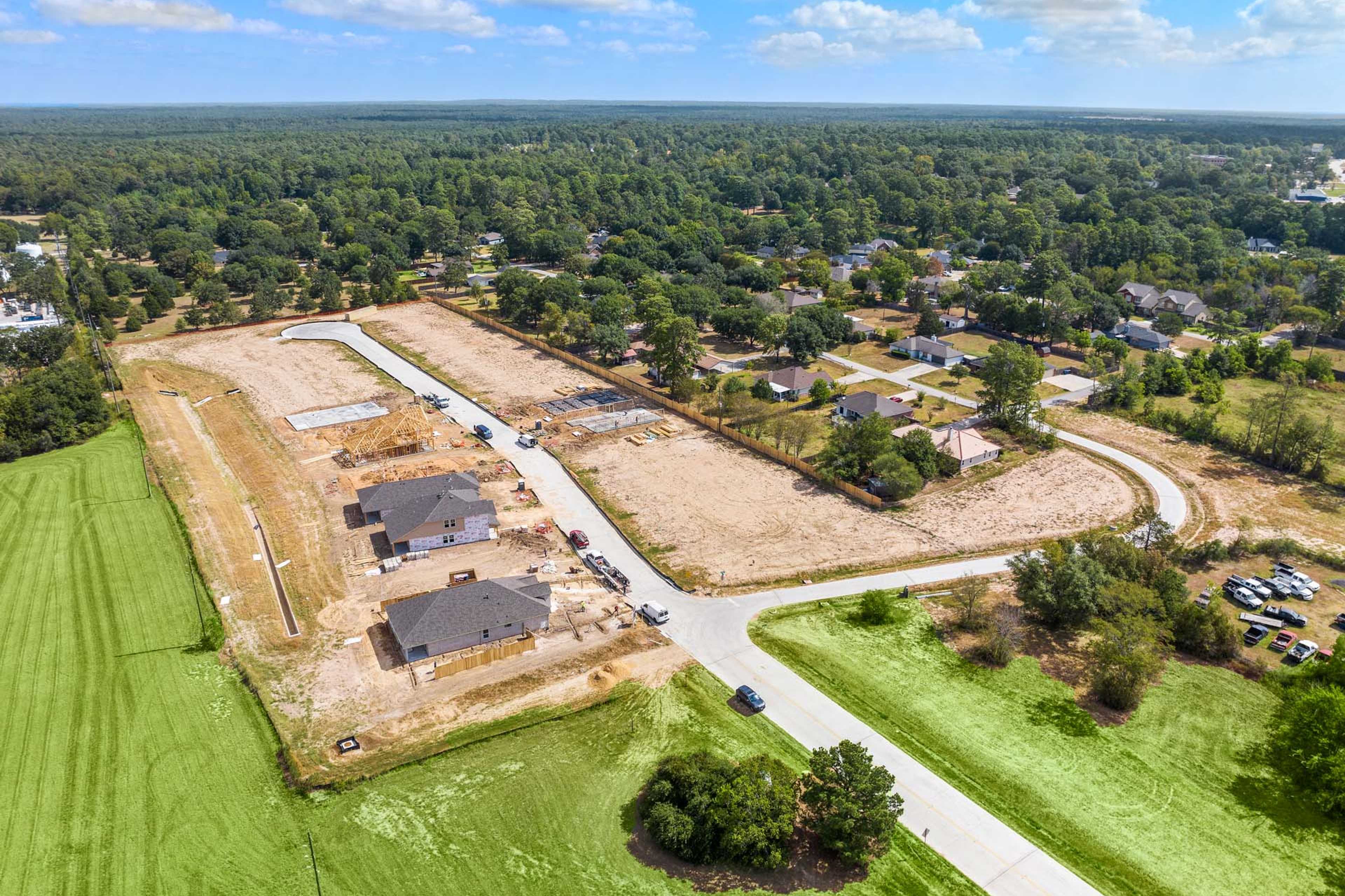 Aerial view of new home construction at Windmill Estates in Magnolia Texas with dirt lots roads and surrounding woods fields
