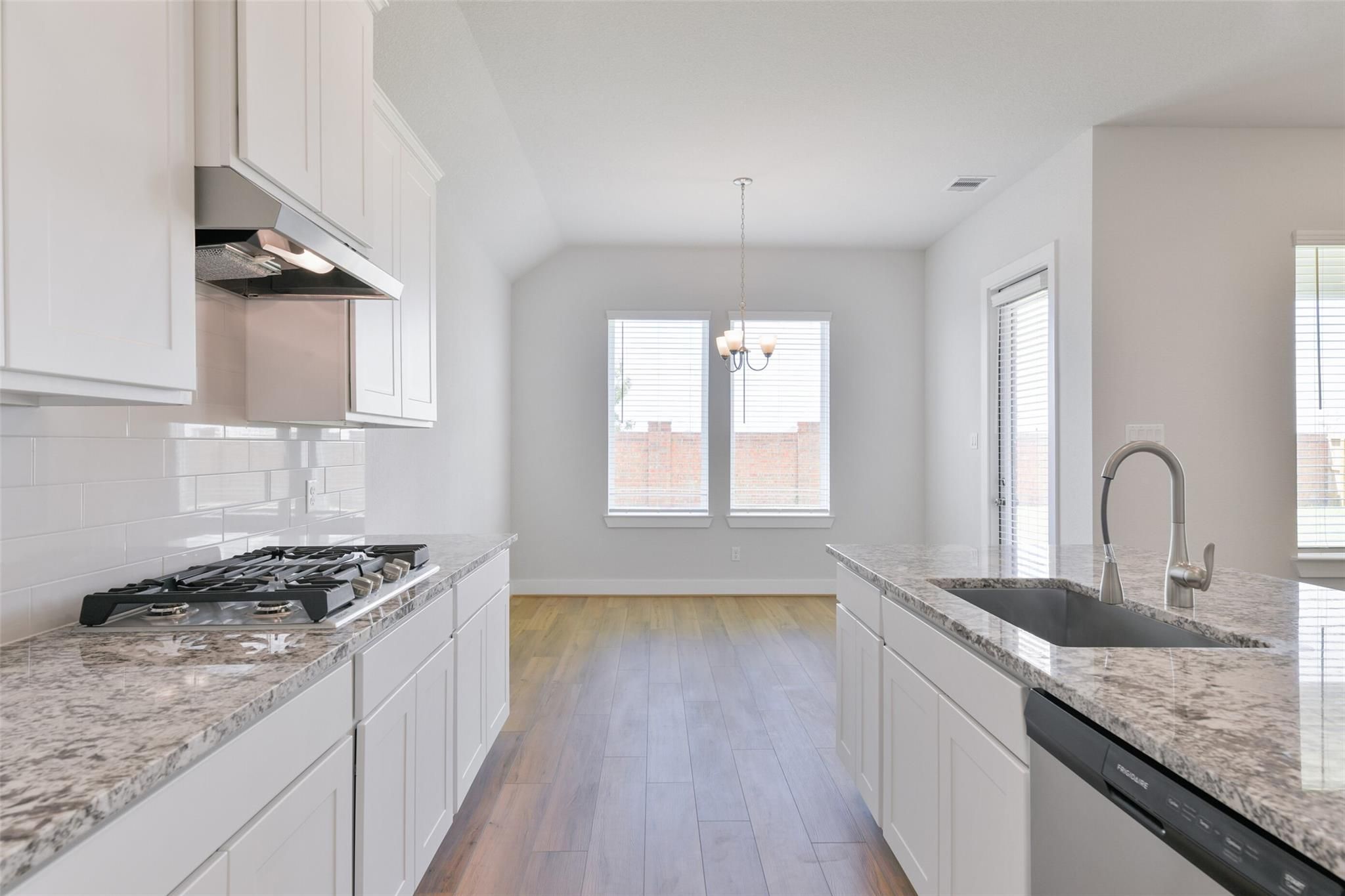 Modern white kitchen with granite counters, stainless appliances, subway tile backsplash in Davidson Homes The Edward A, Lago Mar, Texas City