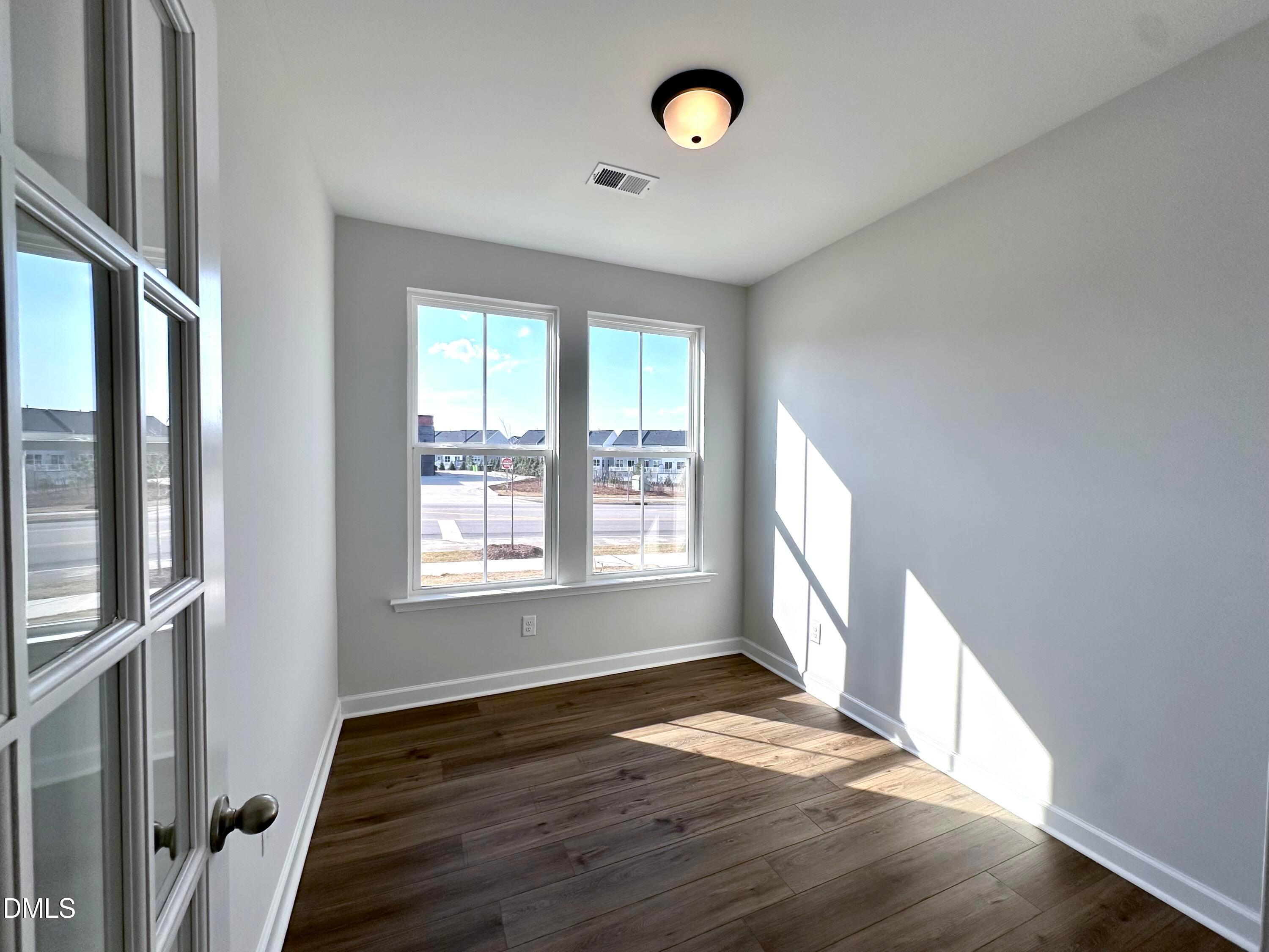 Bright secondary bedroom with large sunny windows, gray walls, hardwood floors in Davidson Homes The Alexander B, Knightdale NC