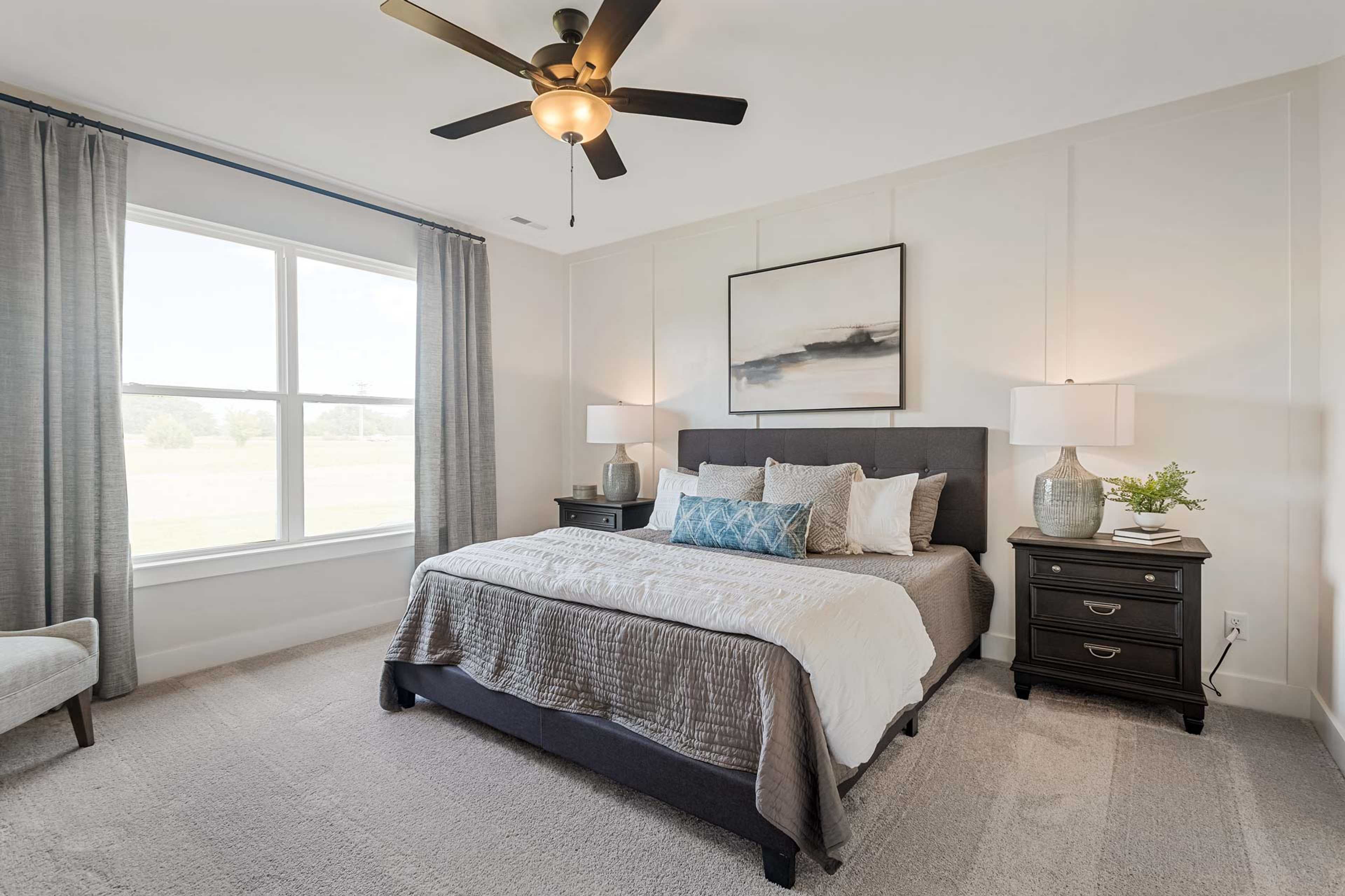 Spacious primary bedroom at Salem Landing in Murfreesboro TN featuring king bed, neutral tones, ceiling fan, and large curtained windows