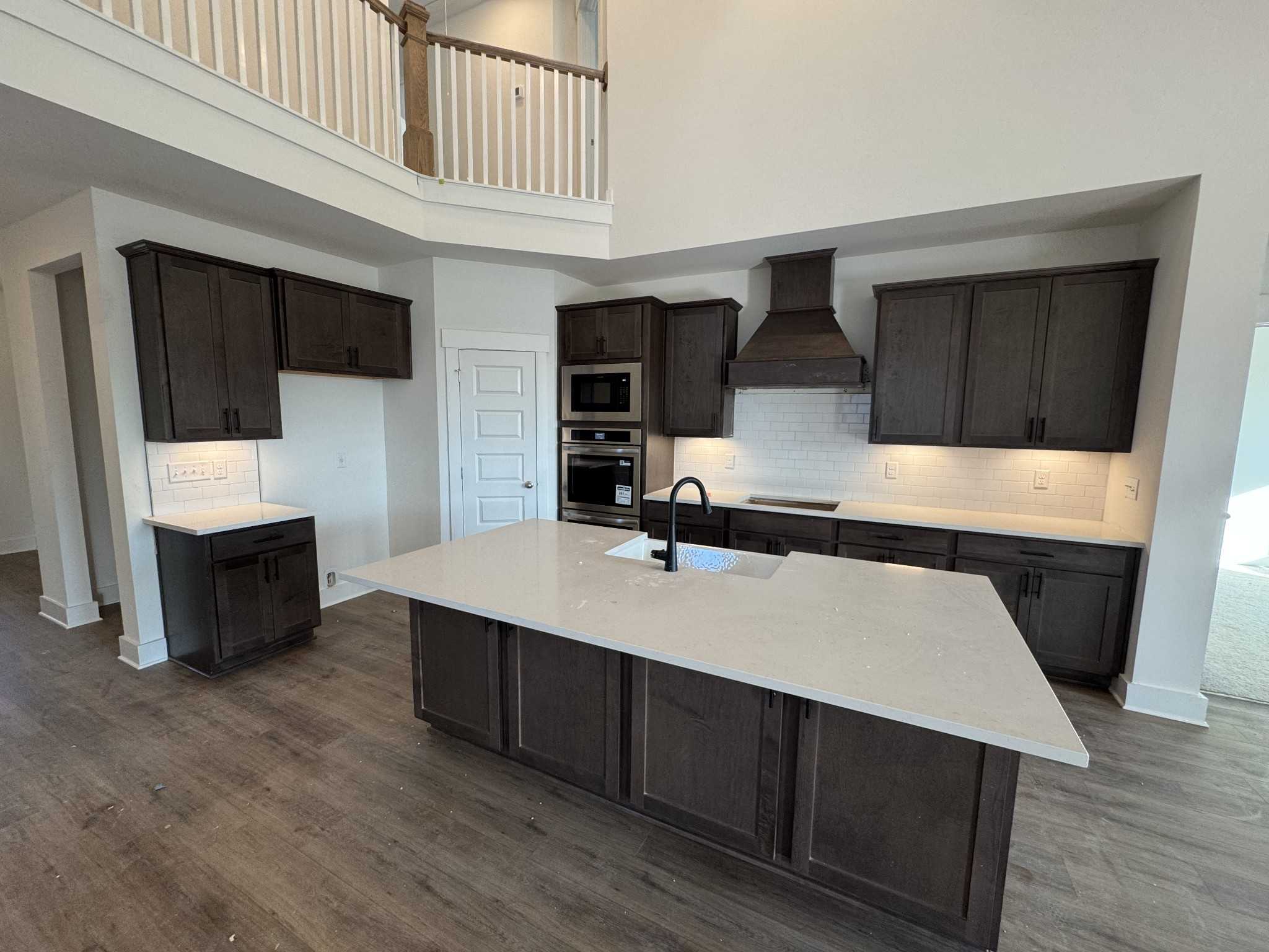 Modern kitchen featuring dark shaker cabinets, quartz island with sink, stainless double oven in Davidson Homes The Ridgeport, Gallatin TN