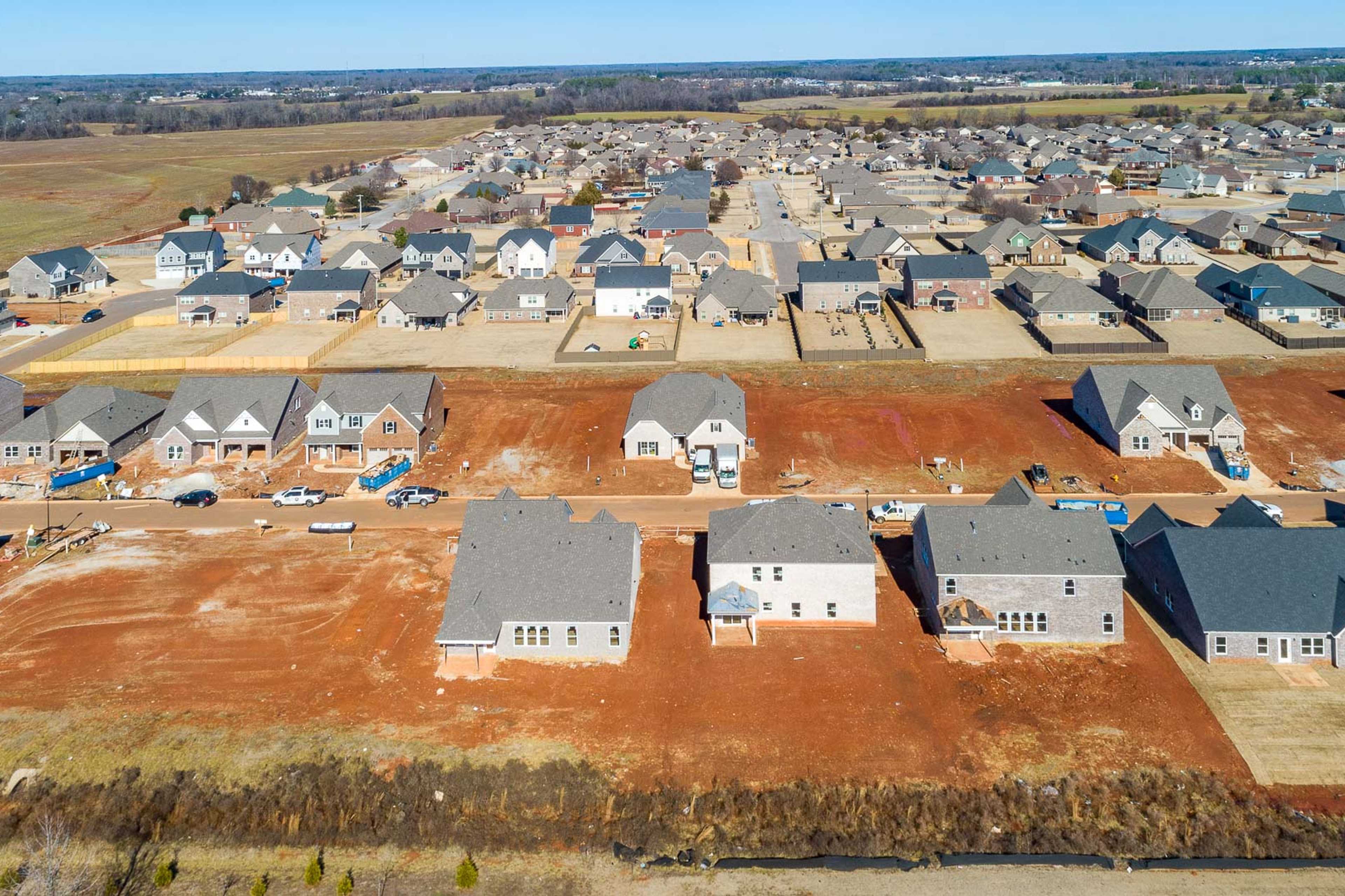 Aerial view of new construction homes in Old Stone Athens Alabama by Davidson Homes with gray roofs red dirt lots and rural surroundings