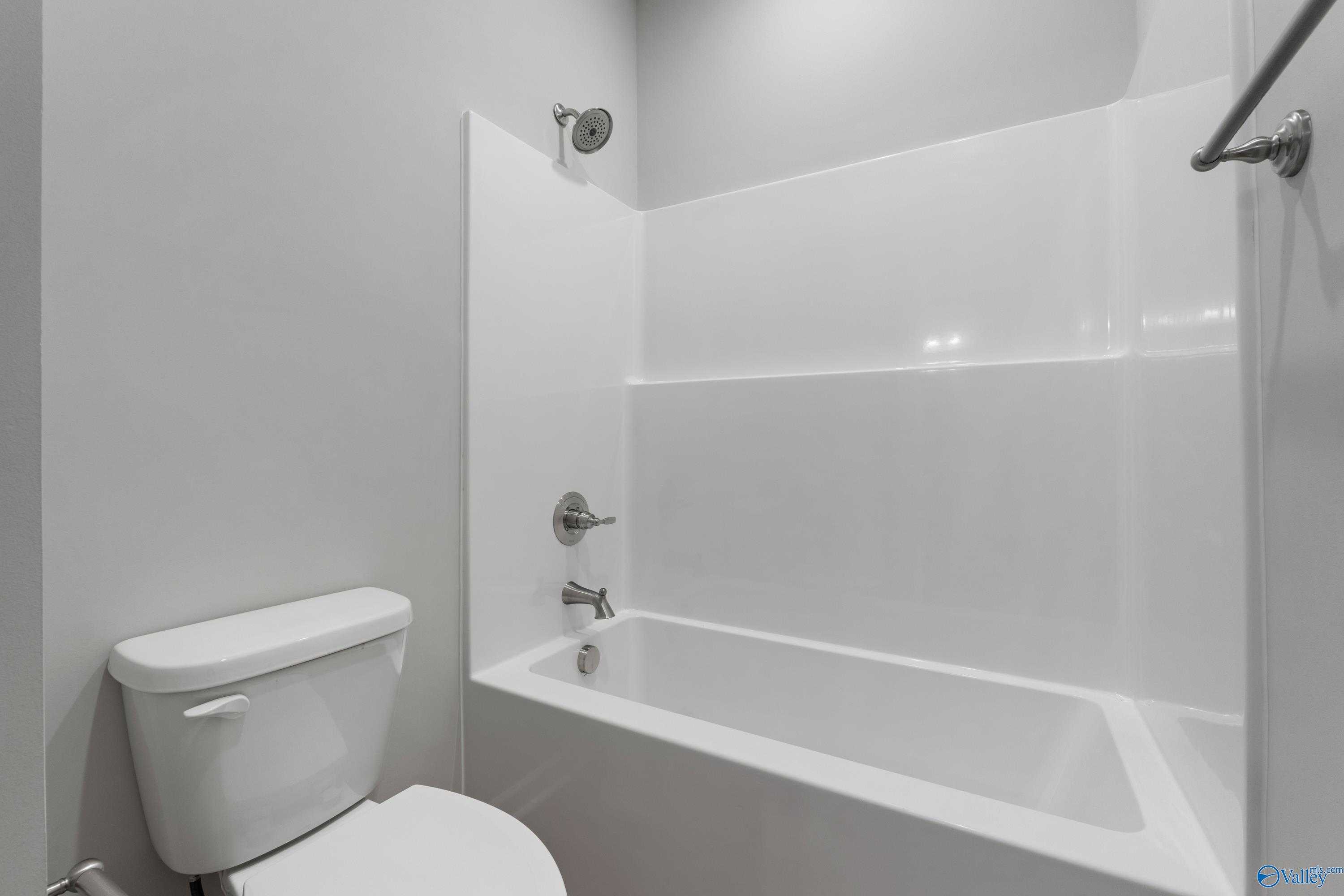 Modern bathroom with white tub-shower combo, chrome fixtures, and gray walls in Davidson Homes The Orion, Athens, Alabama