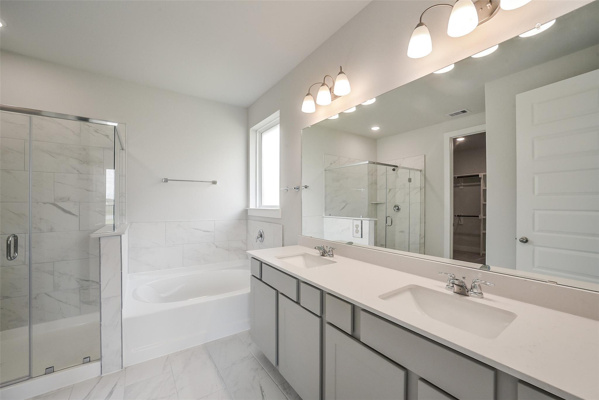 Elegant master bathroom featuring frameless glass shower, soaking tub, double vanity in Davidson Homes The Philip B, Rosharon, Texas