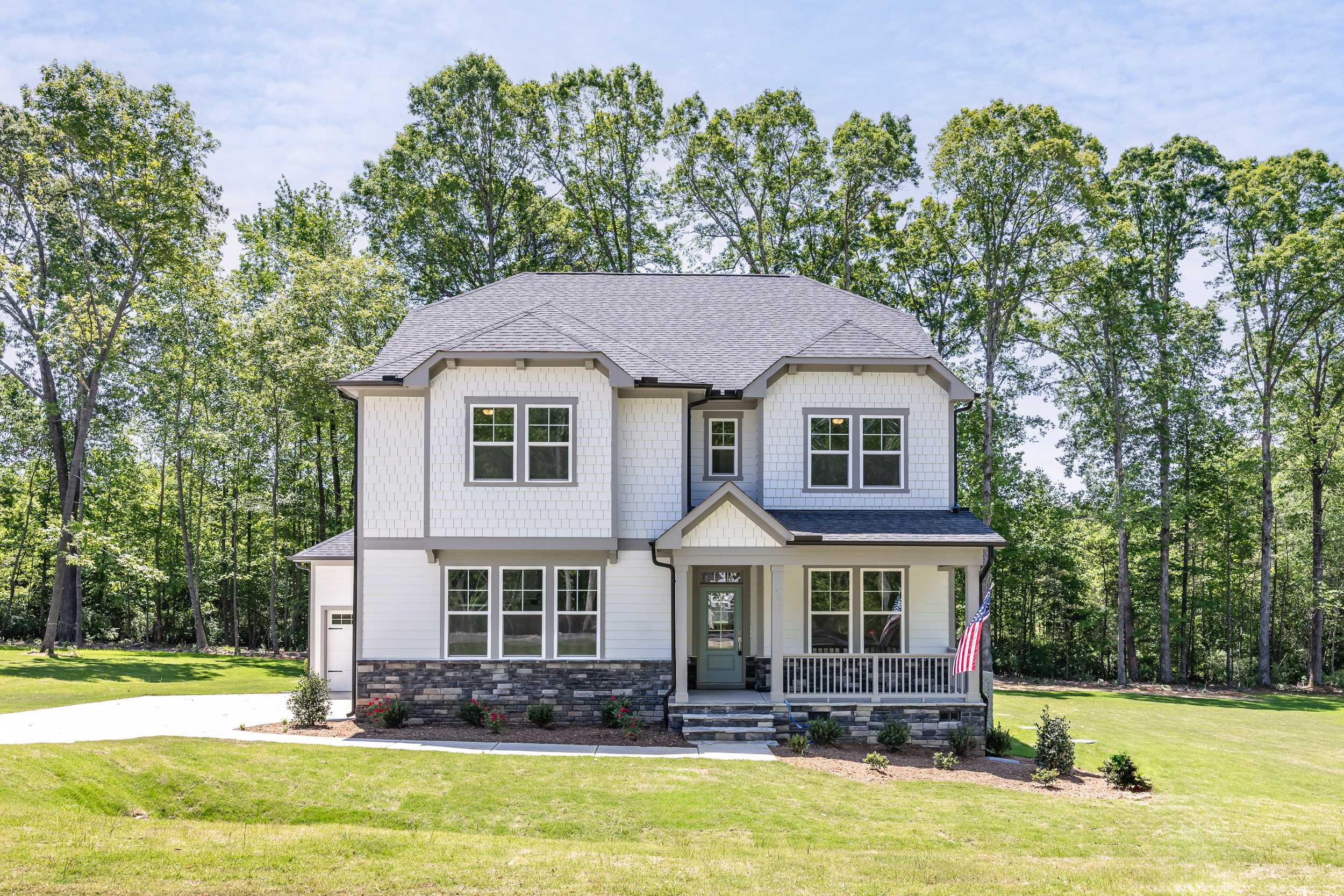 Two-story Beech C home elevation by Davidson Homes with white siding, stone base, covered porch, and lush green yard in Belmont NC
