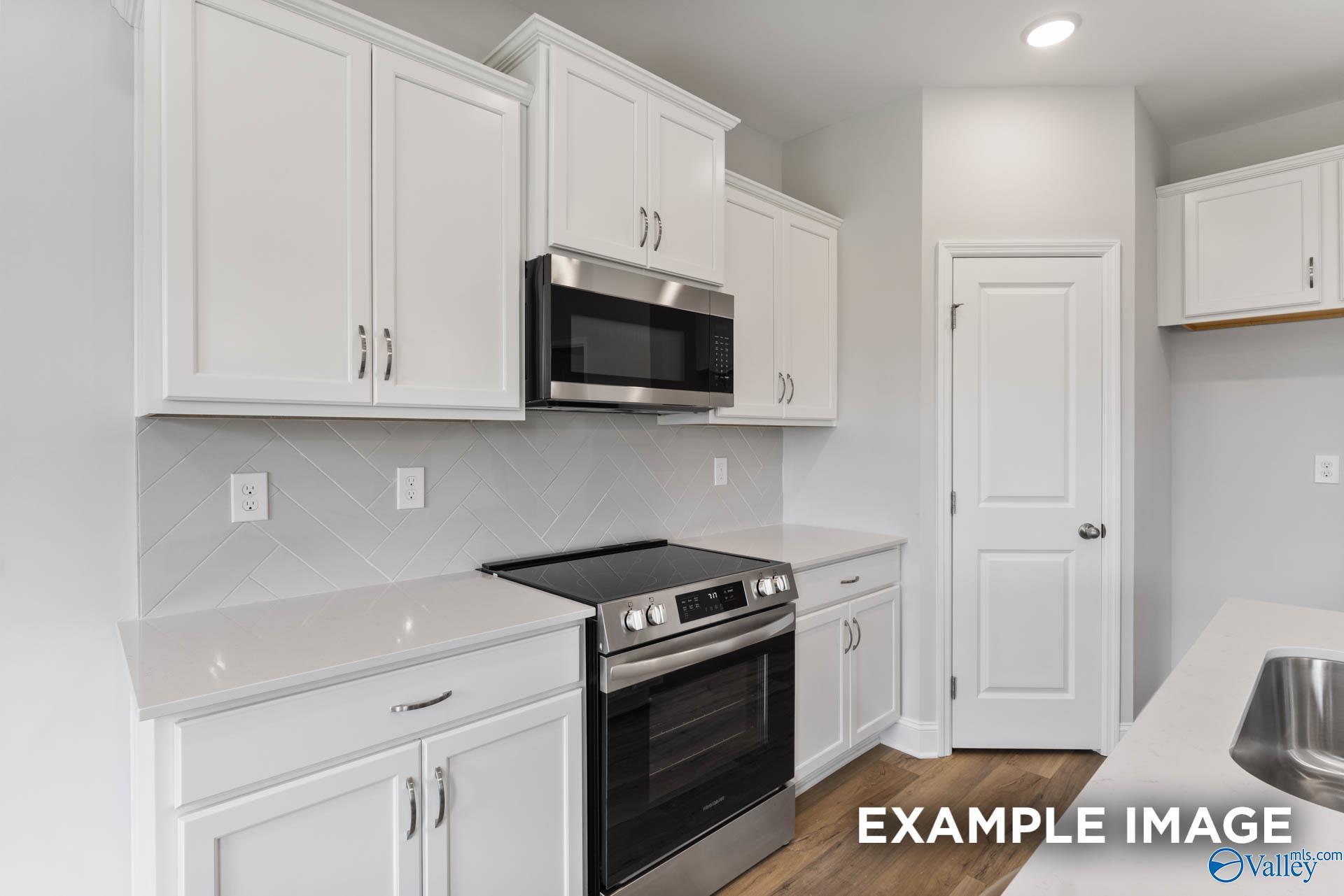 Modern kitchen with white shaker cabinets, stainless steel appliances, and herringbone tile backsplash in Davidson Homes The Butler floor plan