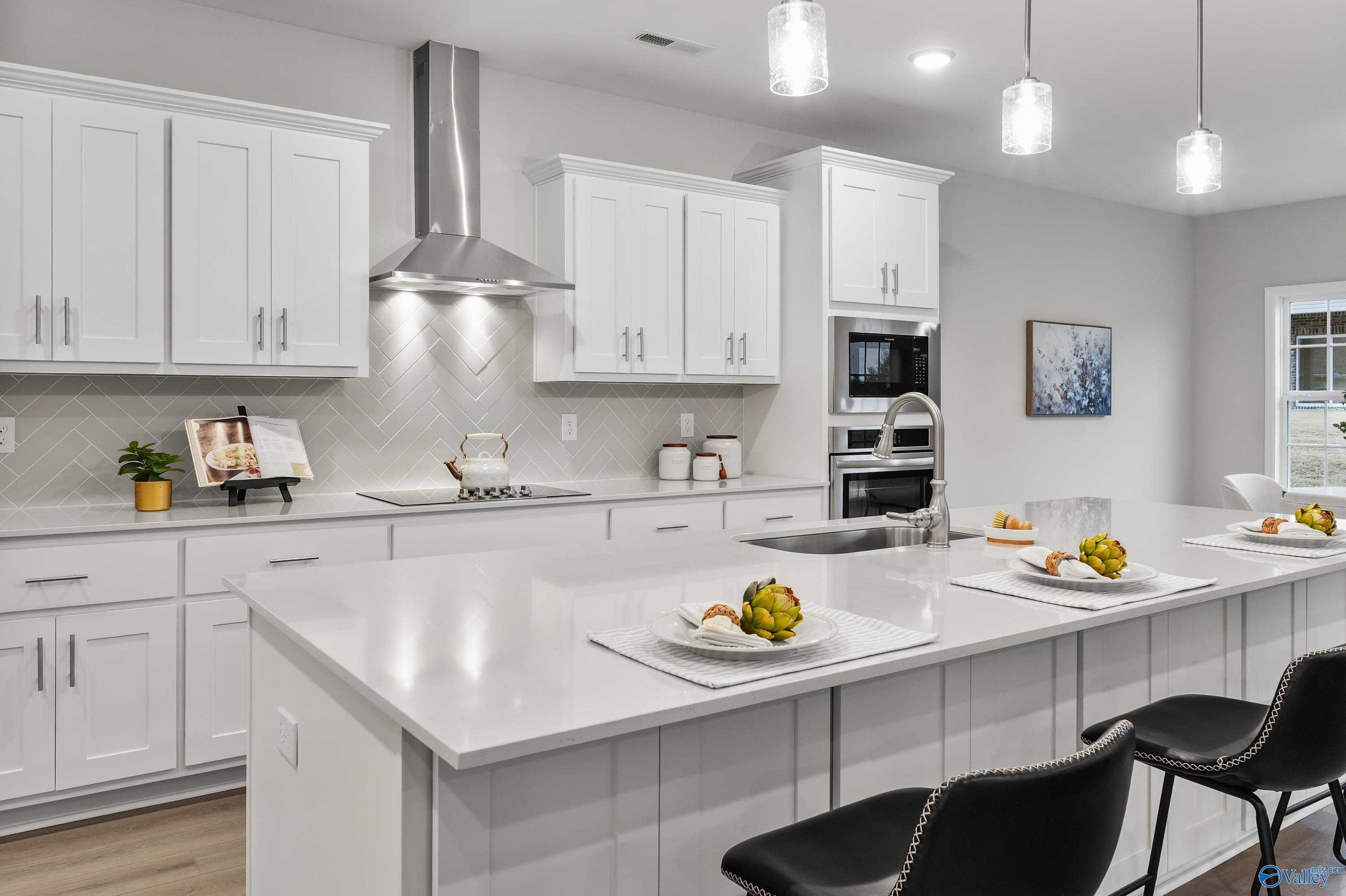 Modern white kitchen with quartz island, stainless appliances, subway tile backsplash in The Finleigh home, Toney, Alabama