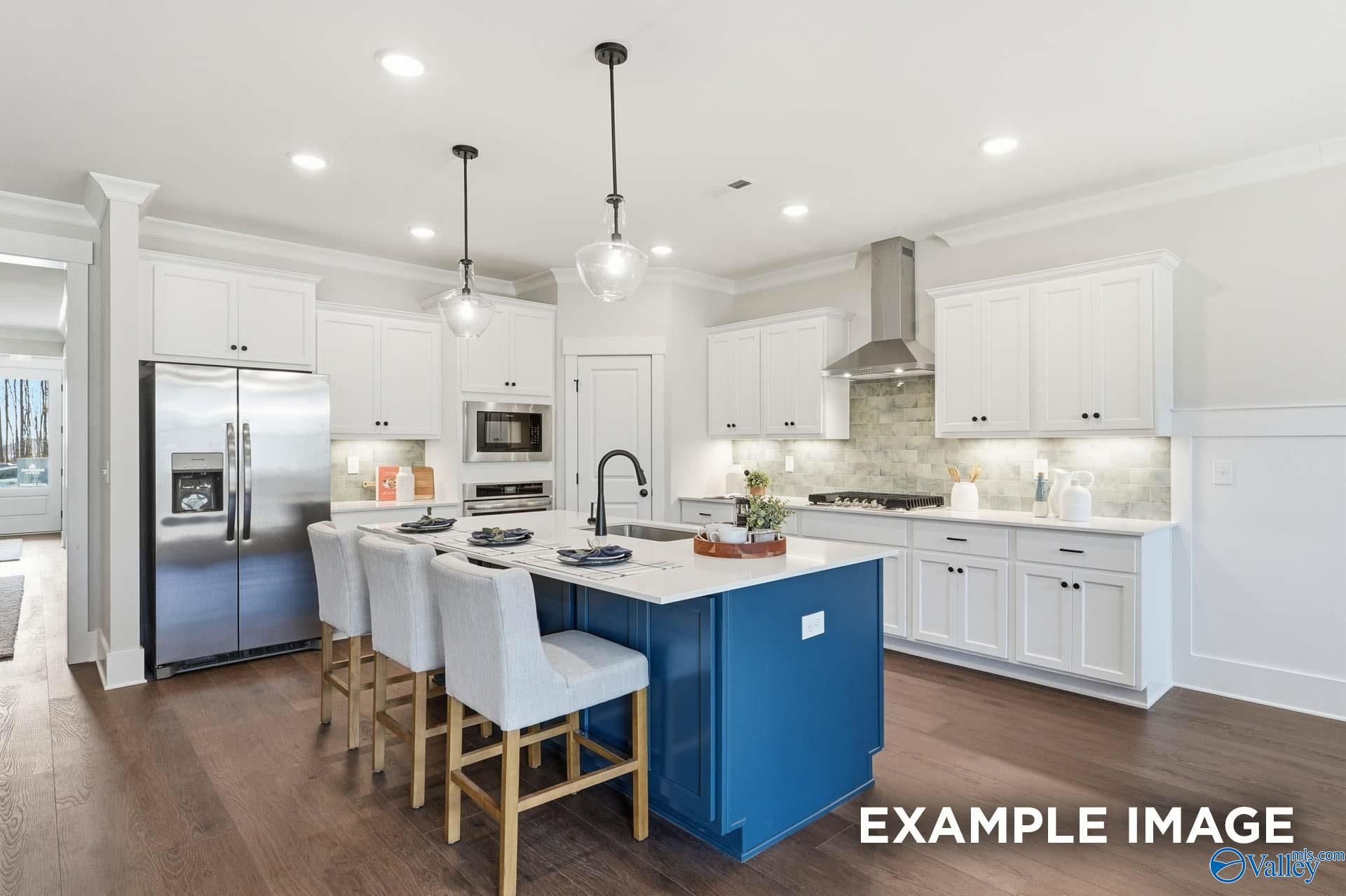 Modern kitchen with blue island, white shaker cabinets, stainless appliances, and pendant lights in Davidson Homes The Hibiscus F, Arab, Alabama
