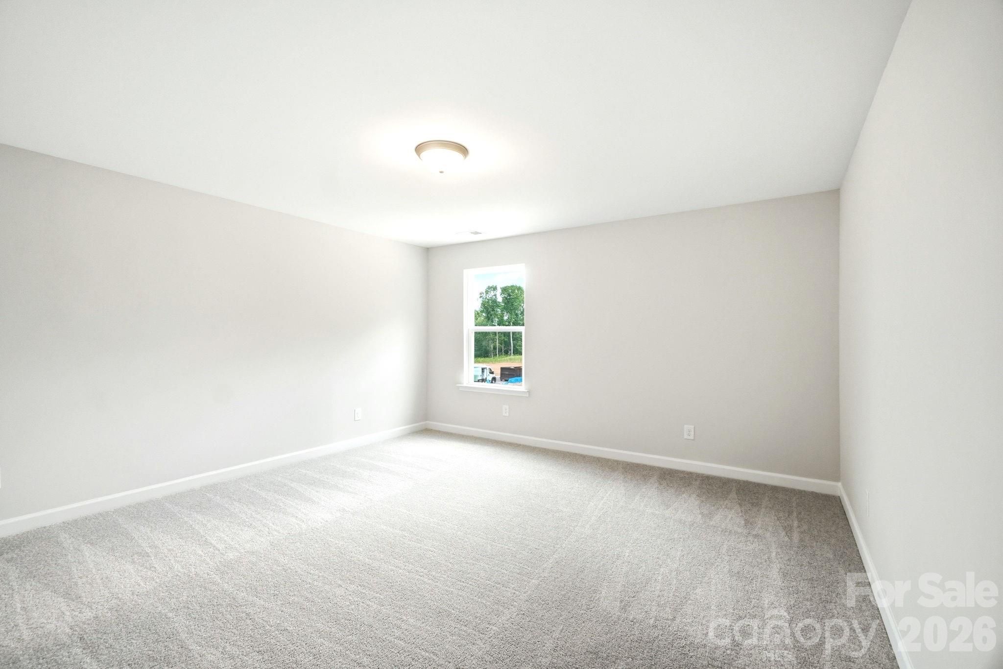 Spacious, carpeted bedroom with neutral walls in The Magnolia B floor plan at Windgate in Mooresville, North Carolina.