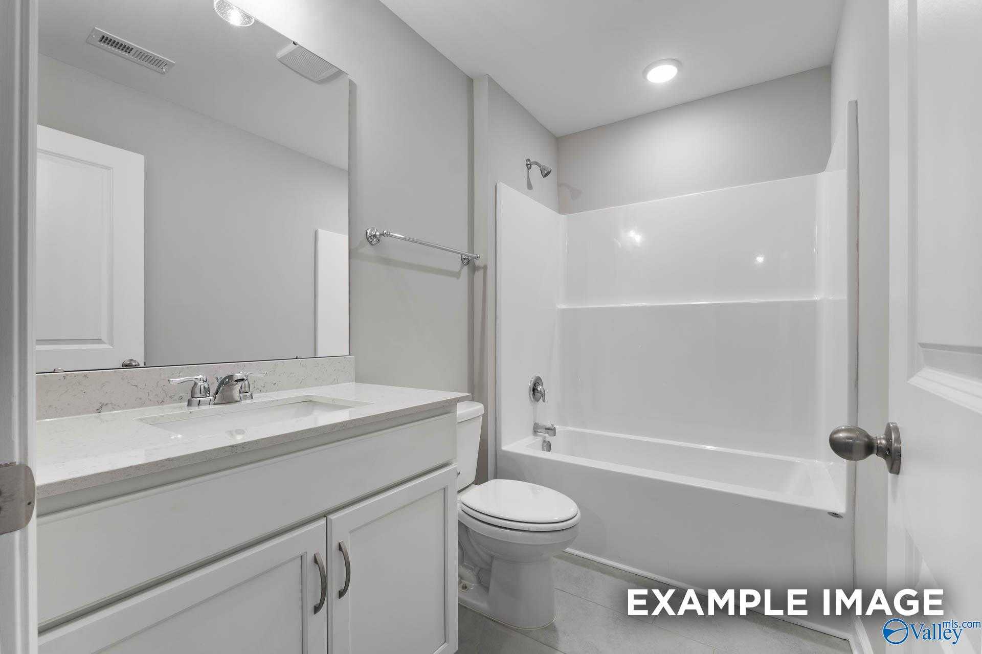 Modern bathroom with white vanity, quartz countertop, and tub-shower combo in Davidson Homes Rockford D, Hazel Green, Alabama