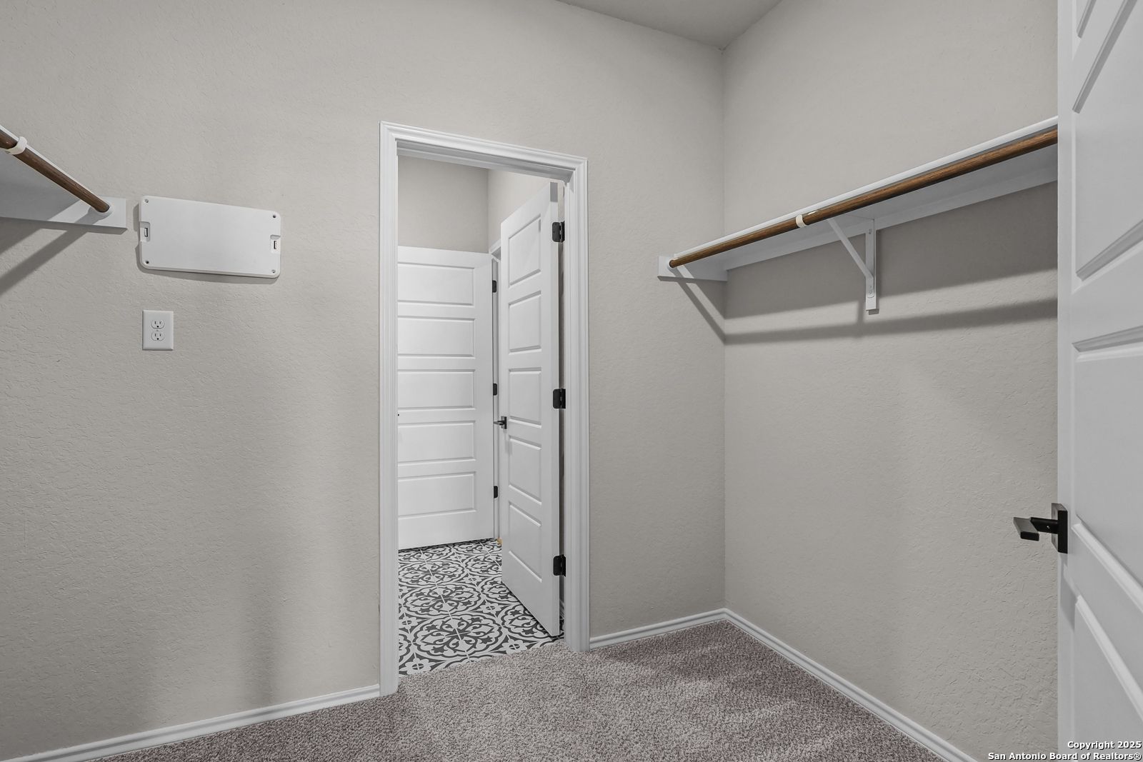 Spacious walk-in master closet with wooden shelving and adjacent bathroom featuring patterned tile in Davidson Homes The Brazos C, San Antonio