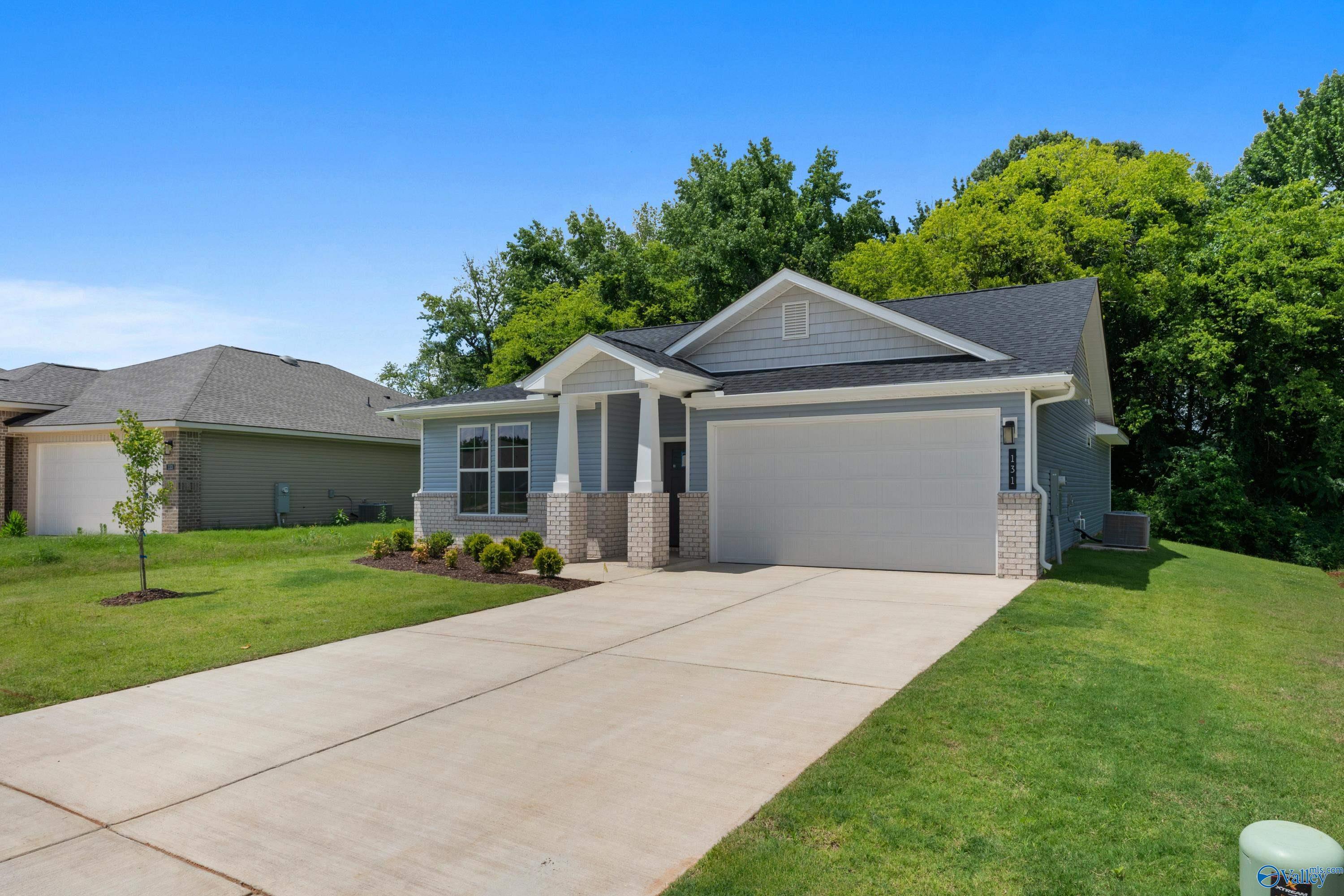 Modern 1-story Phoenix home with gray siding, 2-car garage, driveway, and lush green yard in Forest Glen, Hazel Green, Alabama