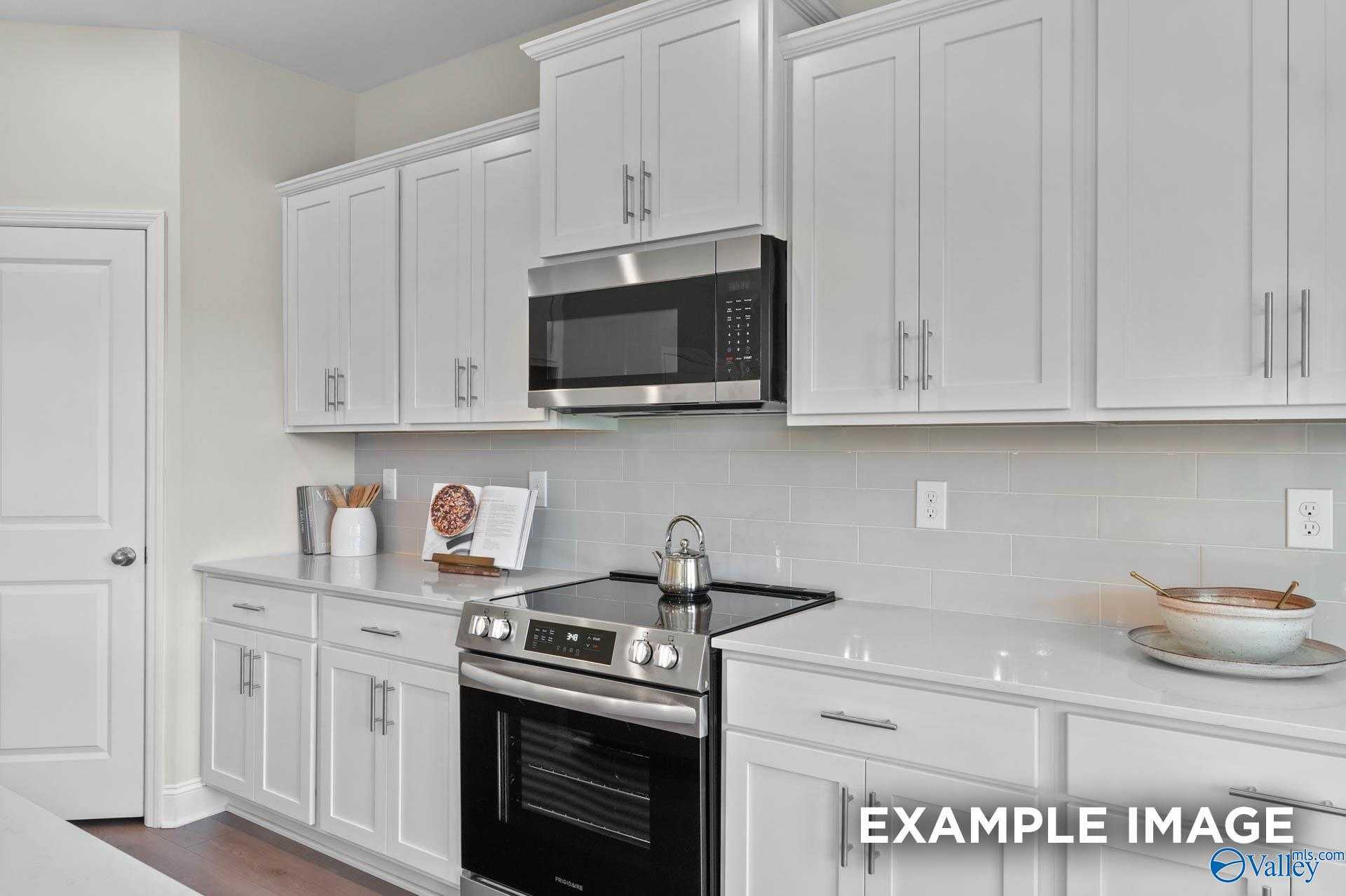 Modern white kitchen with stainless steel oven, microwave, and subway tile backsplash in Davidson Homes The Madison A, Harvest, Alabama
