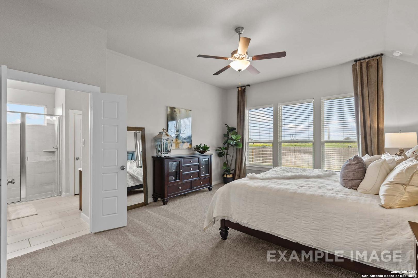 Elegant master bedroom with king bed, wooden dresser, ceiling fan, and en-suite bath in Davidson Homes The Collin A, Seguin, Texas