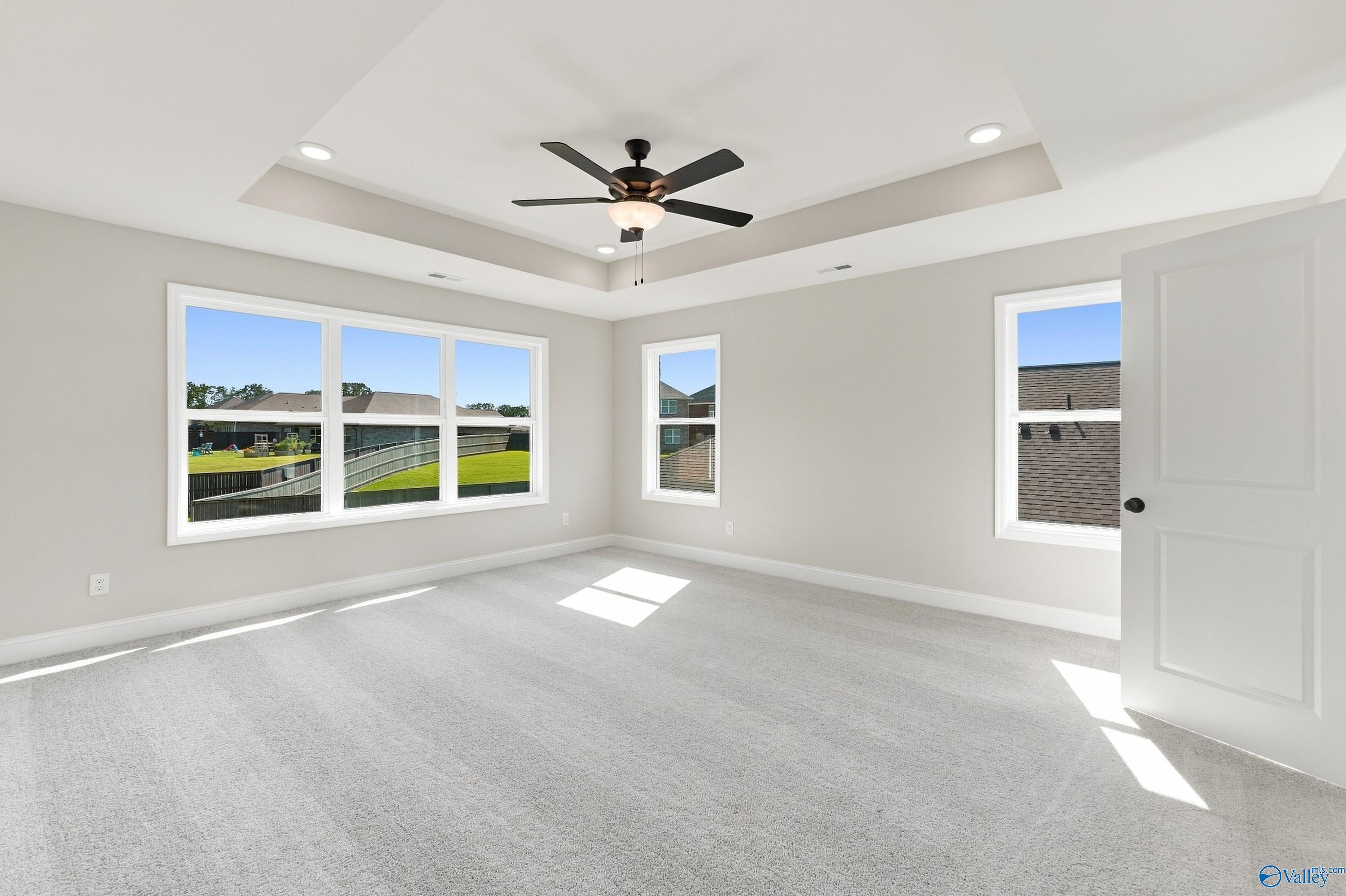 Bright bedroom with tray ceiling, ceiling fan, and large windows in Davidson Homes The Chelsea B, New Market, Alabama