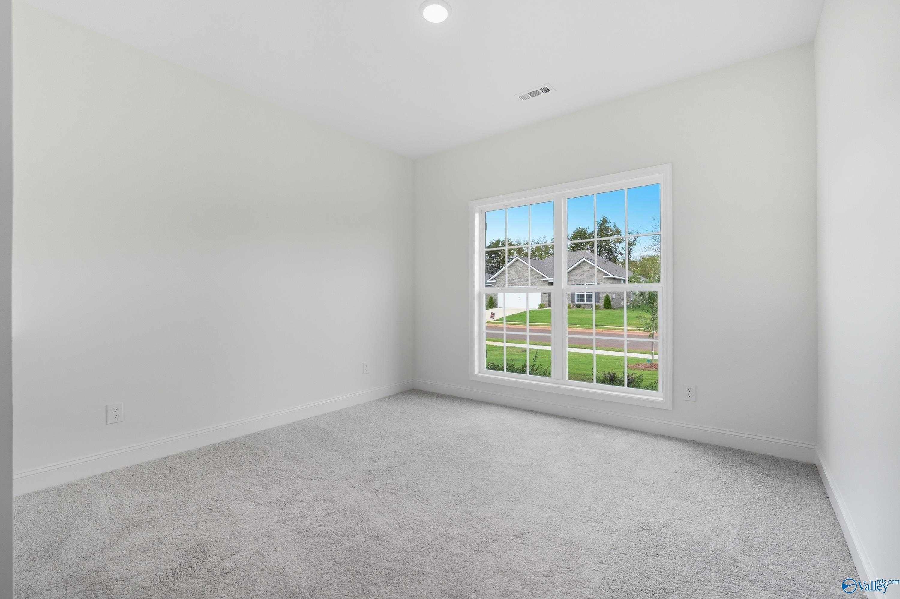 Bright empty bedroom with large window overlooking neighborhood in Davidson Homes The Everett, Meridianville, Alabama