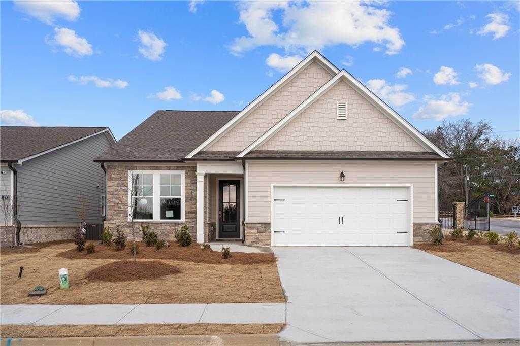 Modern single-story home with beige siding, gabled roof, 2-car garage, and landscaped front yard in Kelly Preserve, Loganville, Georgia