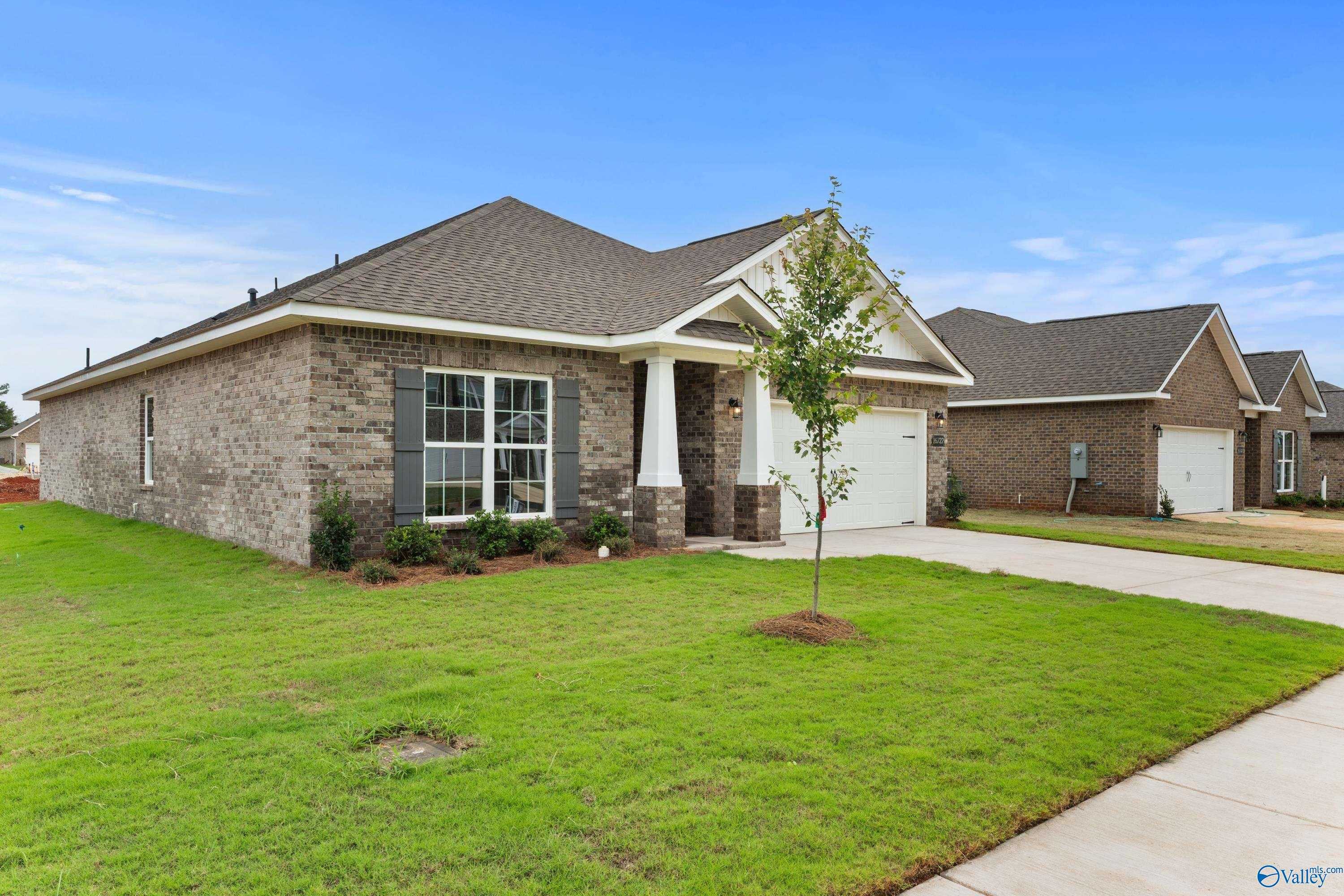Modern single-story brick home with 2-car garage, columned porch, and lush lawn in Ricketts Farm, Athens, Alabama by Davidson Homes The Daphne C