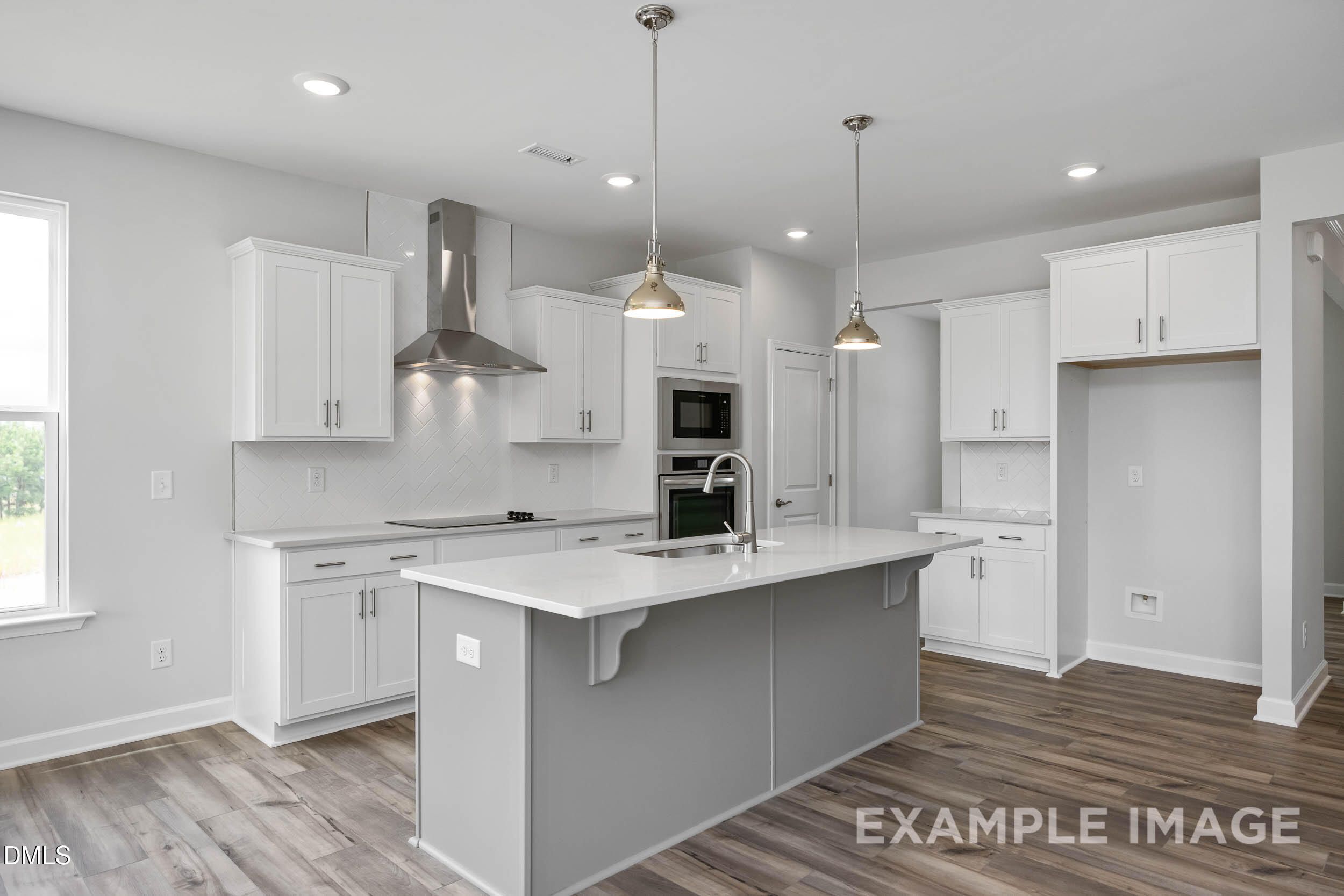 Modern kitchen with white cabinets, gray island, stainless appliances, and recessed lighting in Davidson Homes The Ash B, Lillington, NC