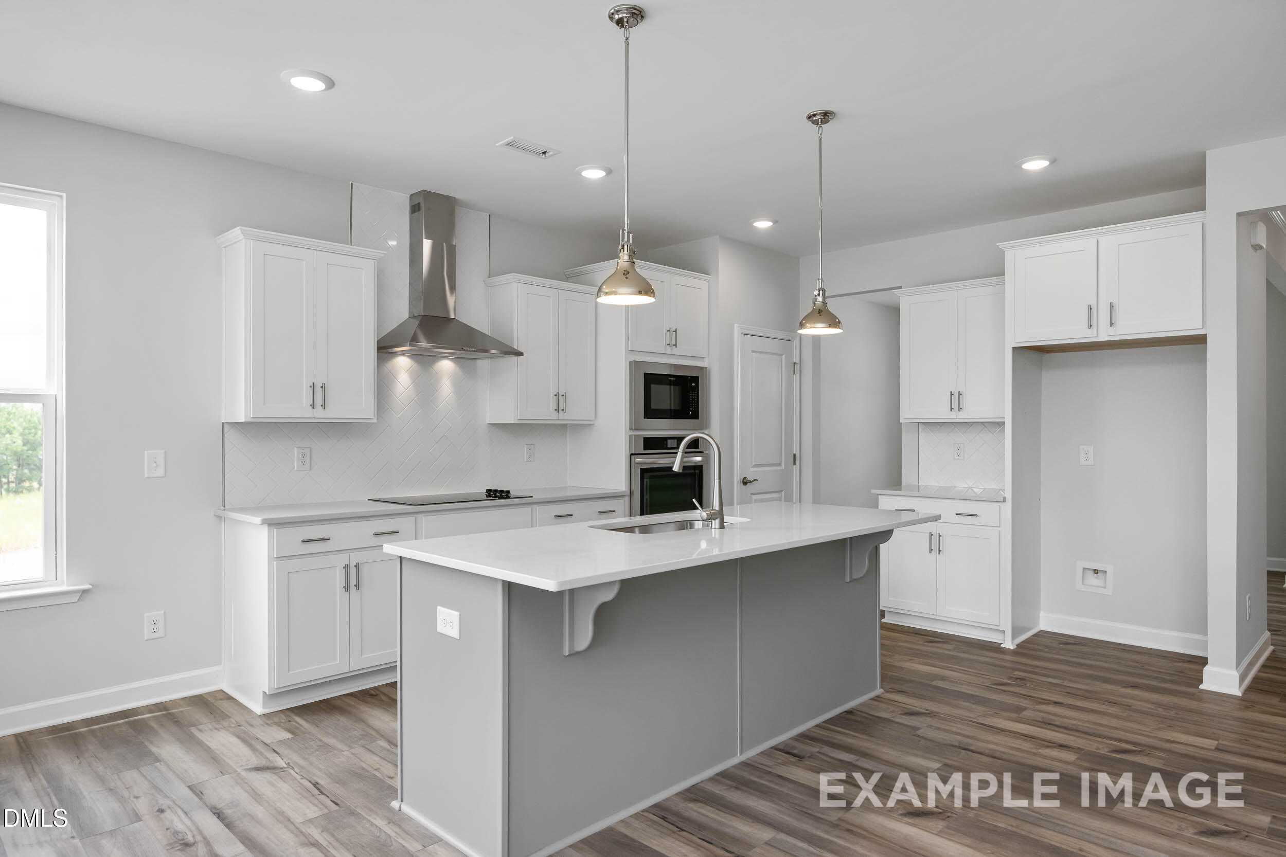 Modern kitchen with white cabinets, gray island, stainless appliances, and recessed lighting in Davidson Homes The Ash B, Lillington, NC