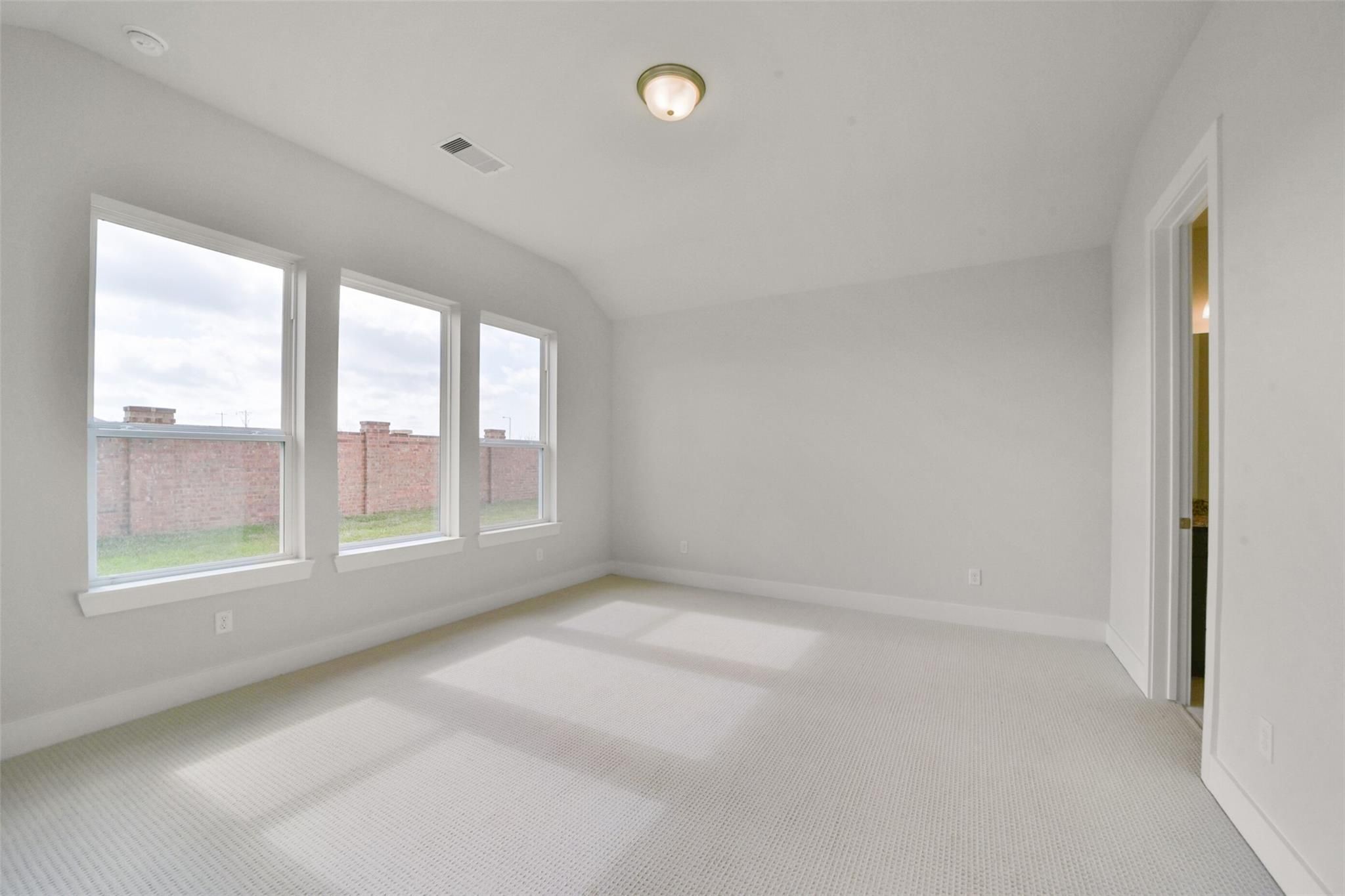Bright upstairs bedroom with three large windows, white walls, and carpeted floor in Davidson Homes The Zion A, Lago Mar, Texas City