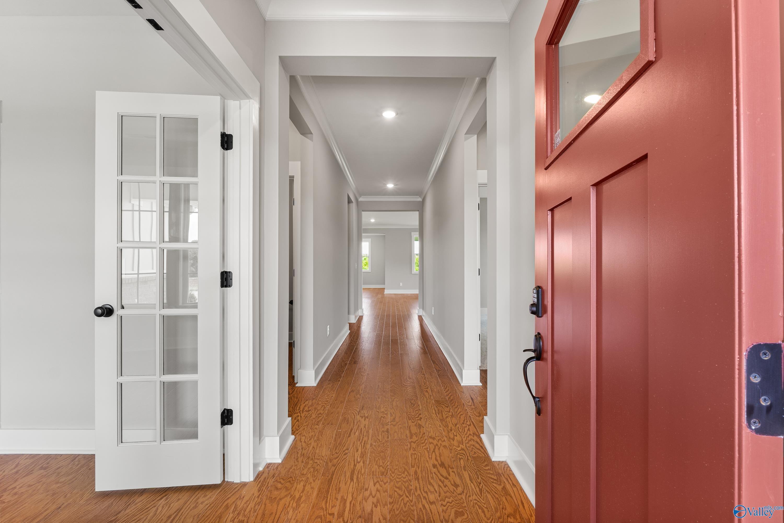 Spacious entry hallway with oak hardwood floors, glass French doors, and red front door in The Arcadia 4-bedroom home, Huntsville, Alabama