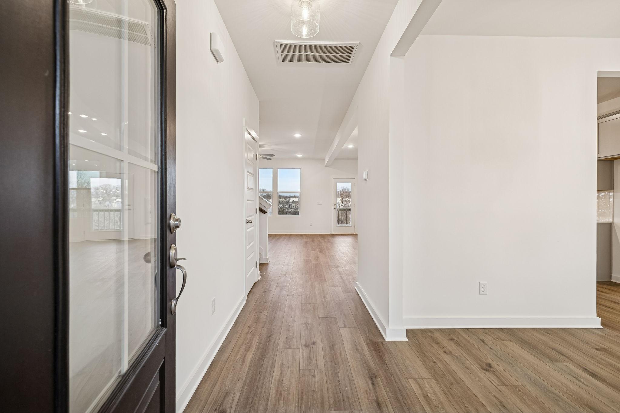Bright entry foyer with glass-paneled front door, hardwood floors, and white walls in Davidson Homes The Willow, Calista Farms, White House, TN