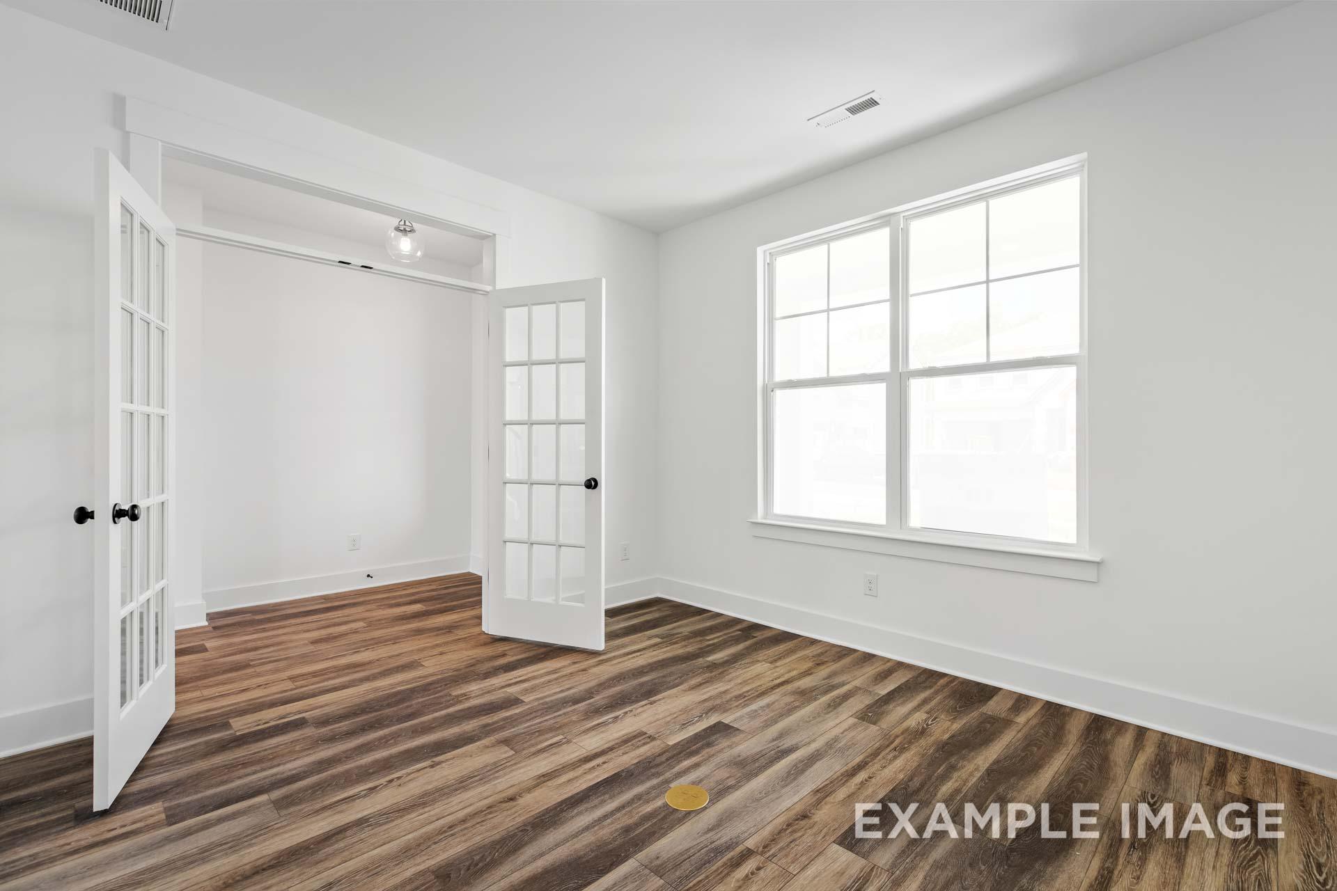 Bright master suite in The Ash C with open French doors, hardwood floors, and large window, Davidson Homes design