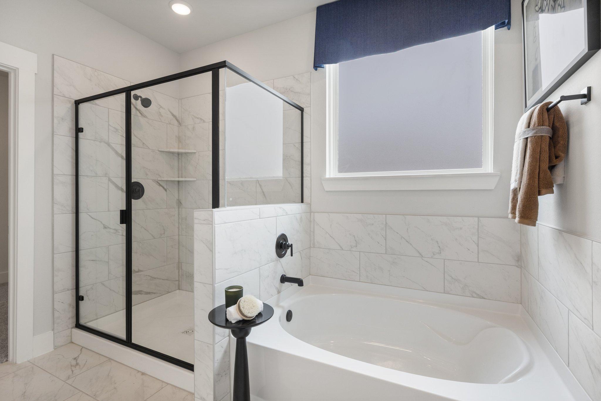 Spacious bathroom at Mercer Meadows in Royse City TX with glass shower, freestanding tub and white subway tile