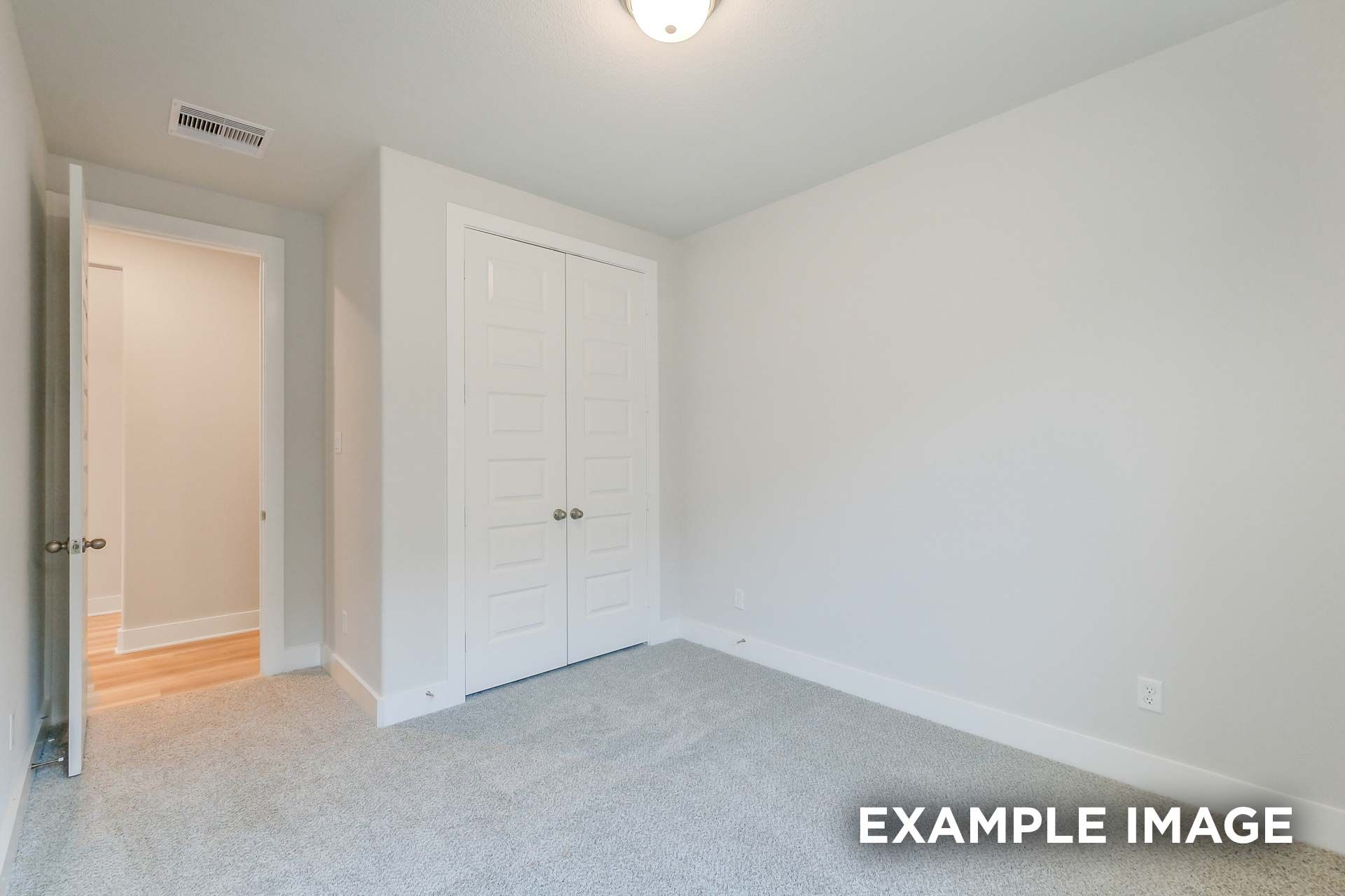 Spacious secondary bedroom in The Luna K with white walls, gray carpet, bi-fold closet doors, and bathroom entry