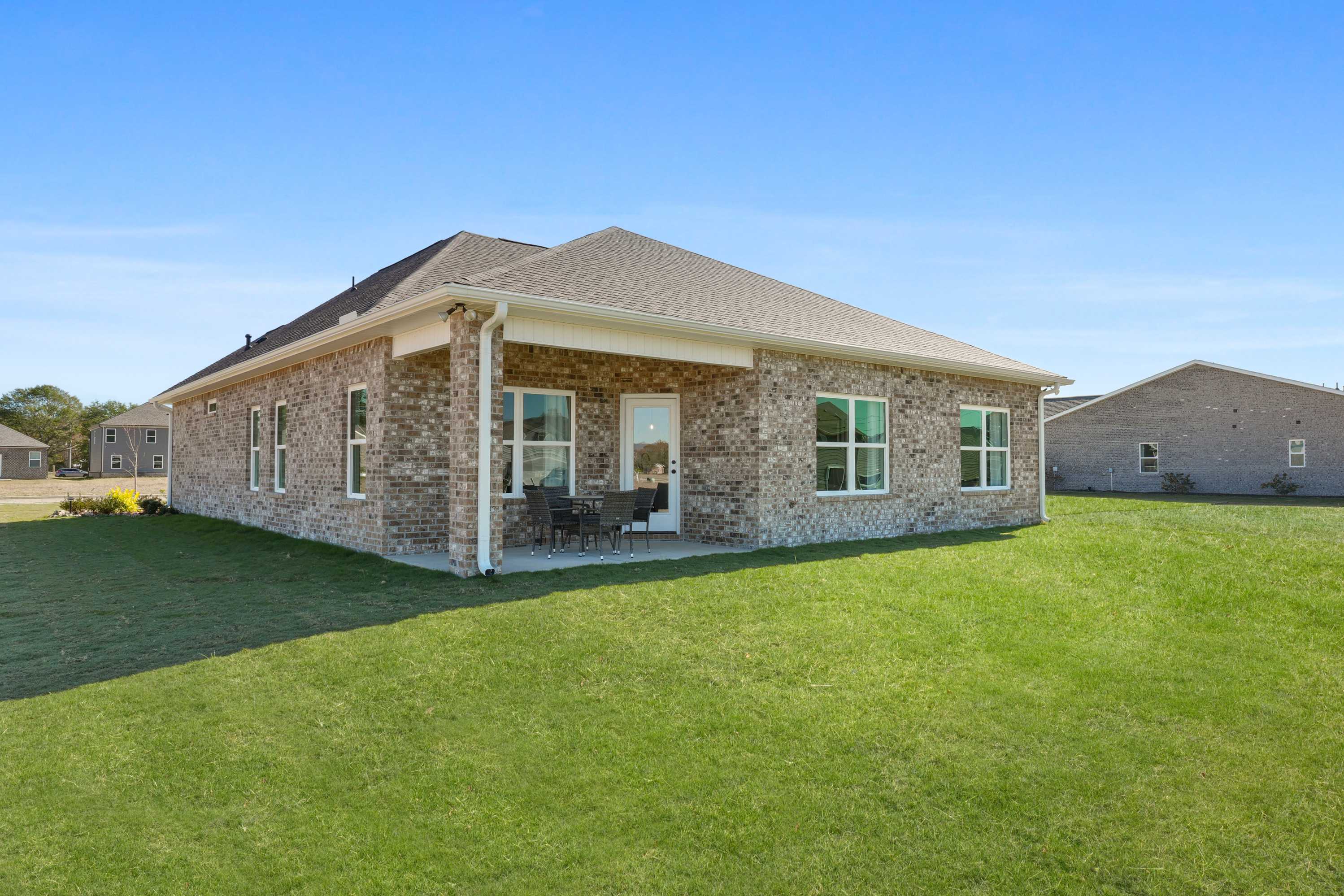 Brick ranch home exterior in Ramsay Cove, Owens Cross Roads Alabama with covered porch, brick facade, and lush green lawn