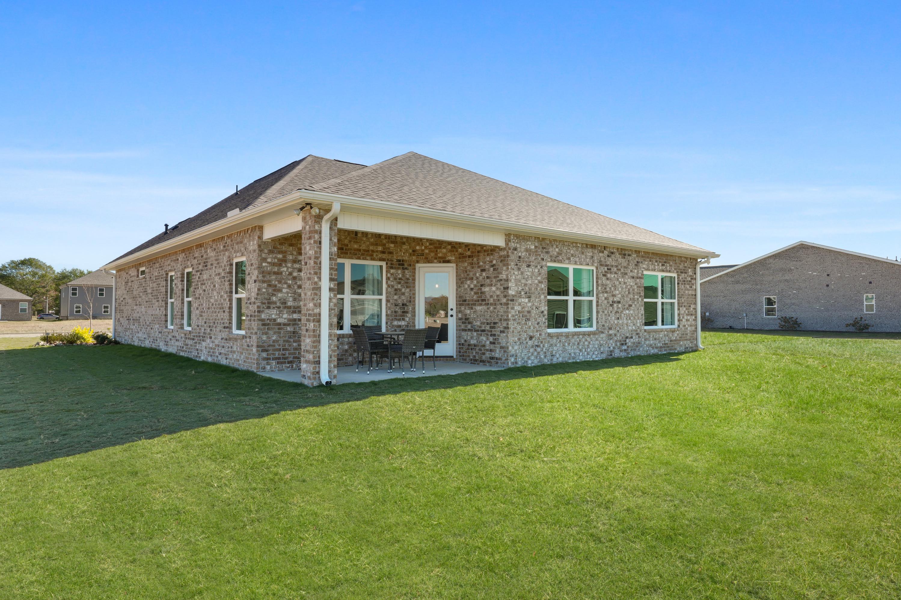 Brick ranch home exterior in Ramsay Cove, Owens Cross Roads Alabama with covered porch, brick facade, and lush green lawn