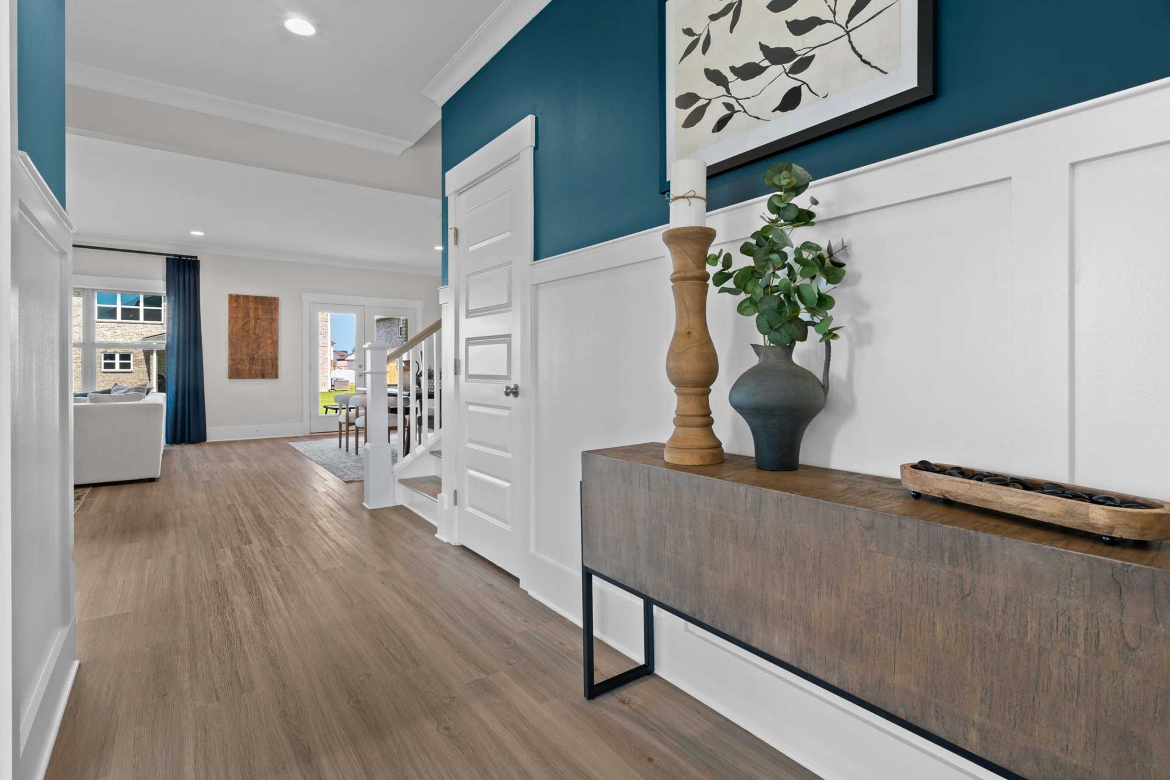 Elegant foyer hallway at Walker's Hill in Meridianville AL with navy accent wall, white wainscoting, hardwood floors, and wooden console table