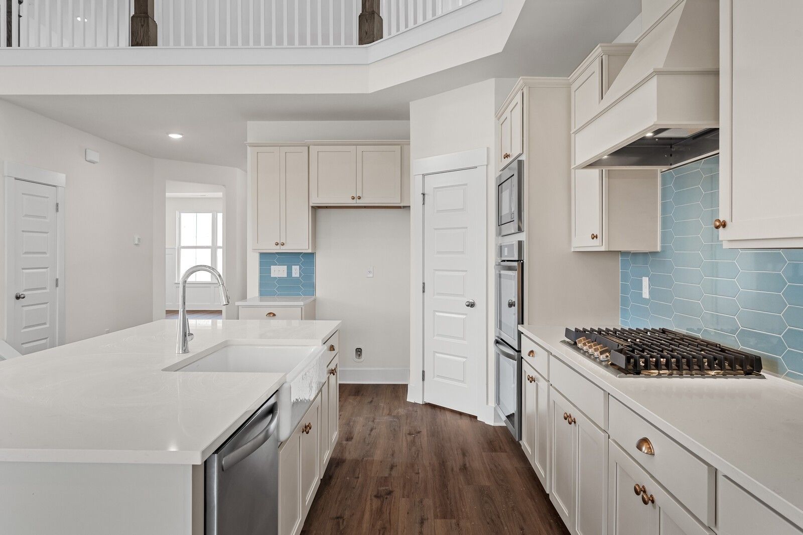 Modern kitchen featuring white shaker cabinets, blue subway tile backsplash, quartz island, and stainless appliances in Davidson Homes The Ridgeport, Gallatin, TN