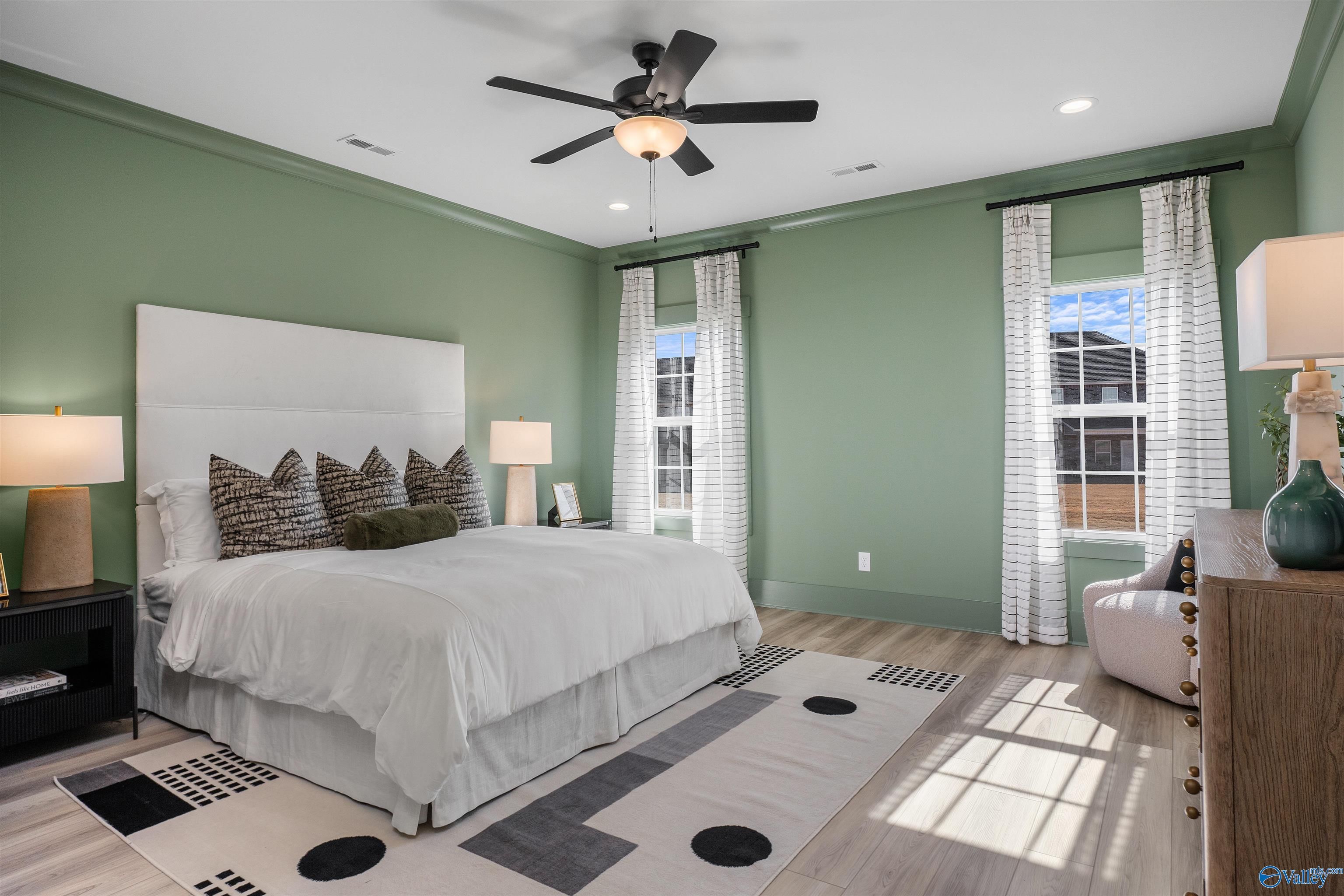 Serene green-walled bedroom with king bed, ceiling fans, and large windows in Davidson Homes The Rockford B, Madison Alabama