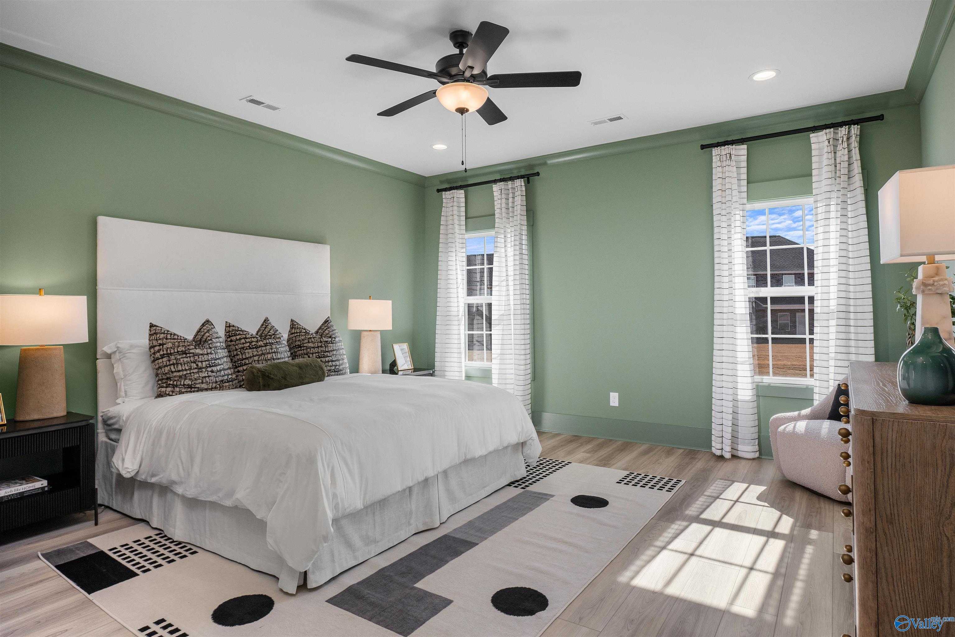 Serene green-walled bedroom with king bed, ceiling fans, and large windows in Davidson Homes The Rockford B, Madison Alabama
