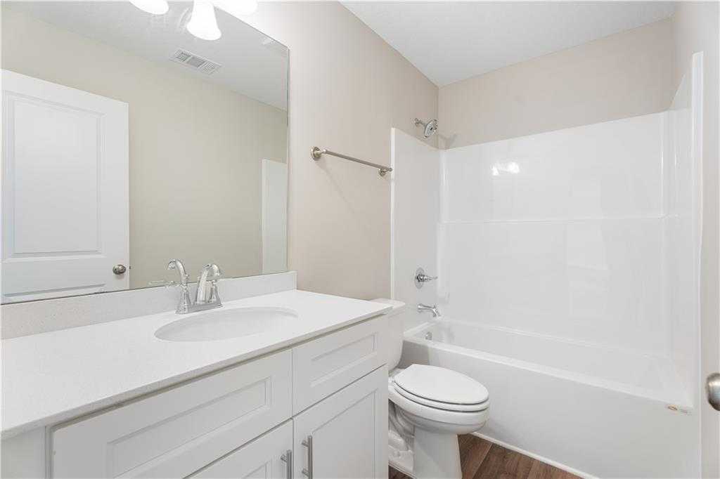 Bright secondary bathroom featuring white vanity, tub-shower combo, and toilet in Evermore Homes The Washington, Phenix City, Alabama
