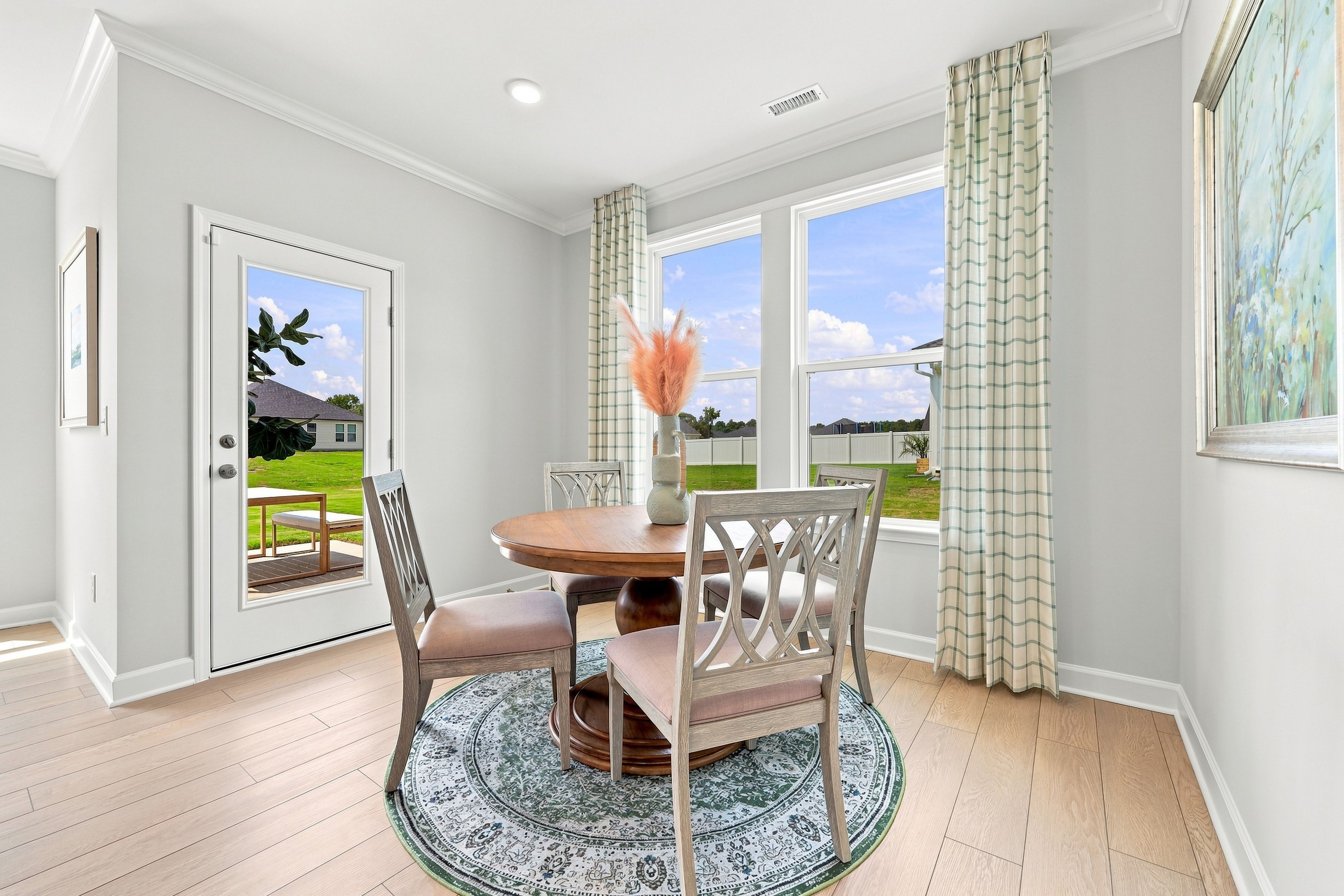 Bright breakfast nook in The Daphne C featuring a round dining table, patterned area rug, and access to the backyard.